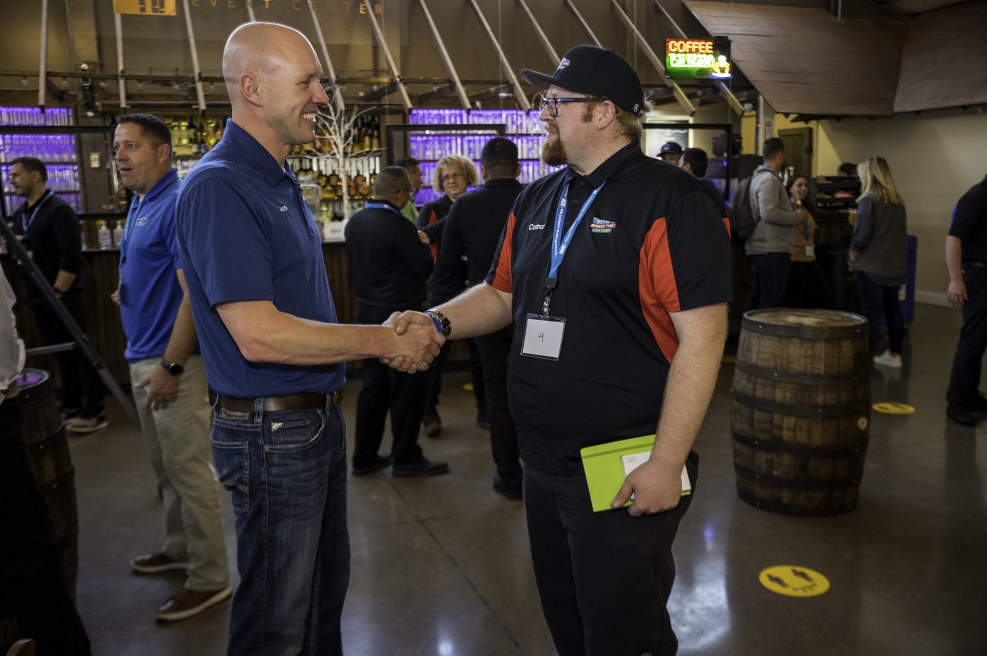 Two men are shaking hands in a crowded room.