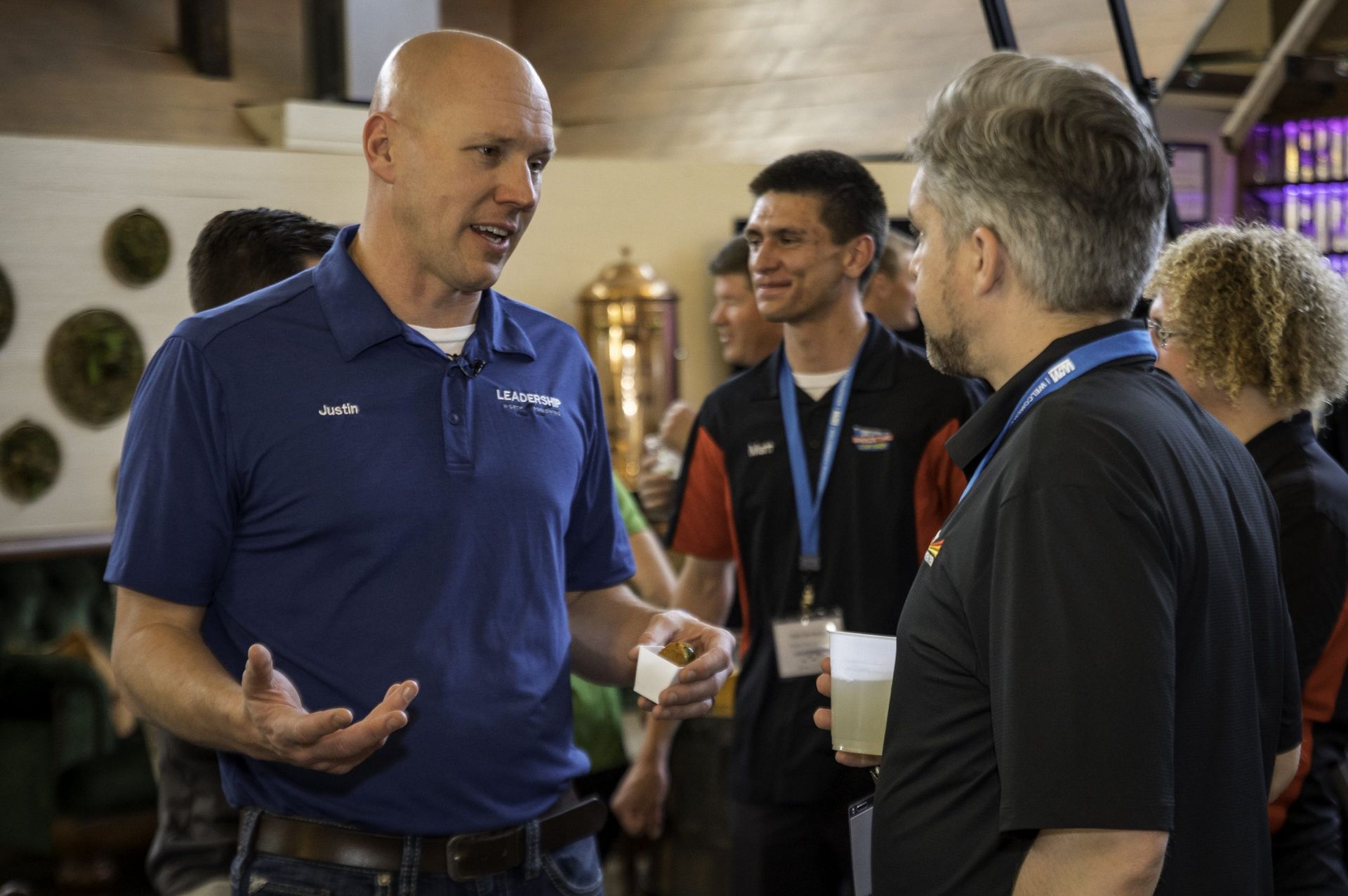 A group of men are standing around talking to each other in a room.