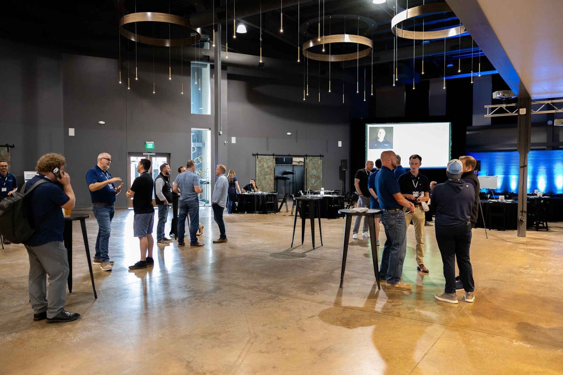People networking at Leadership Worth Following car wash convention in a large room with a stage in the background.