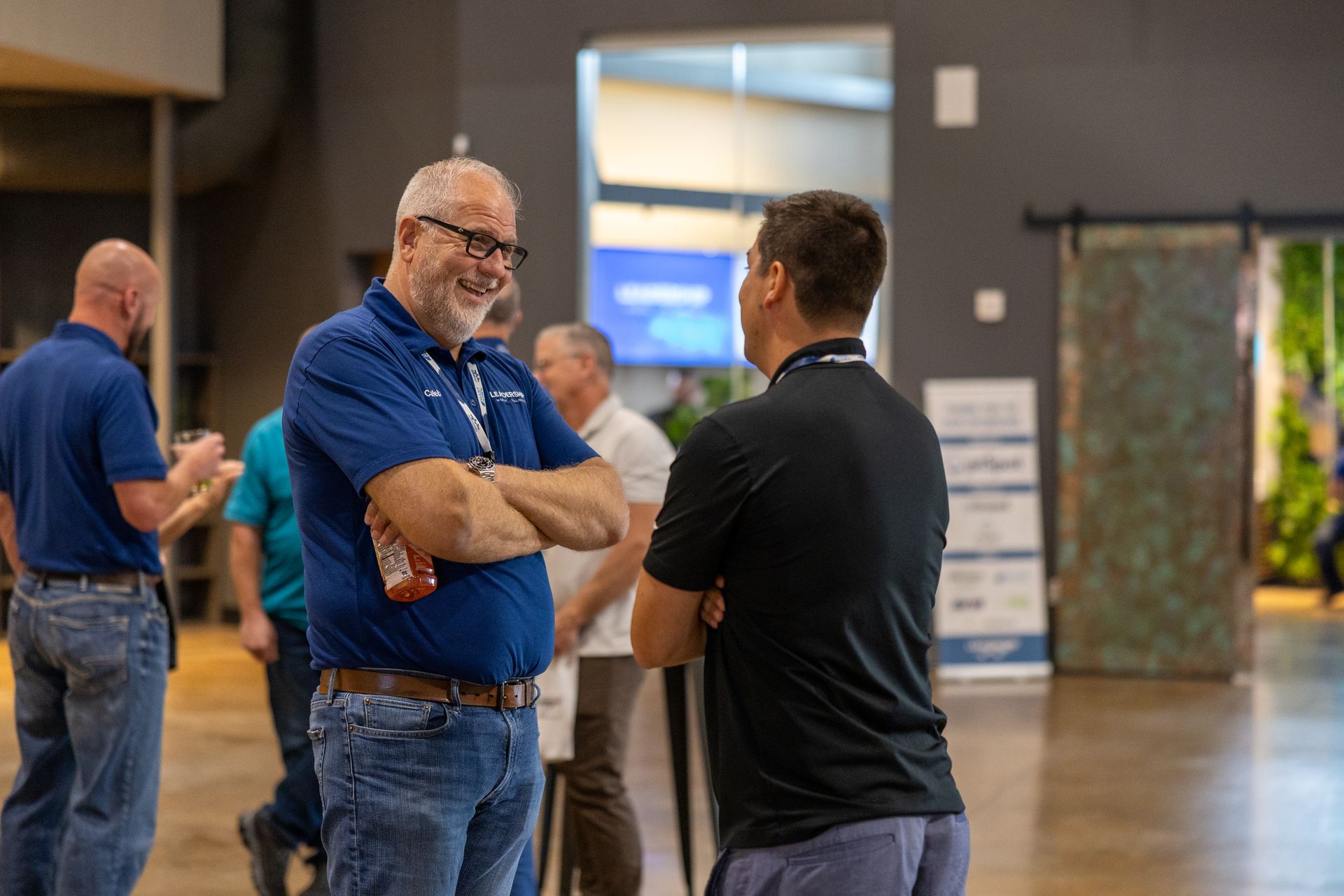 Two men at Leadership Worth Following car wash convention talking. One with glasses and a blue shirt, the other in black.