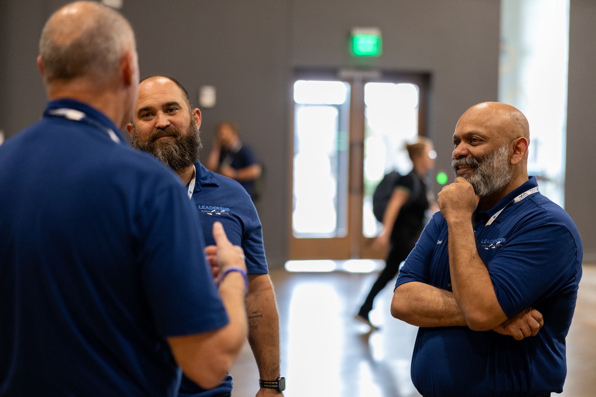 Three men in blue shirts talking at Leadership Worth Following car wash convention