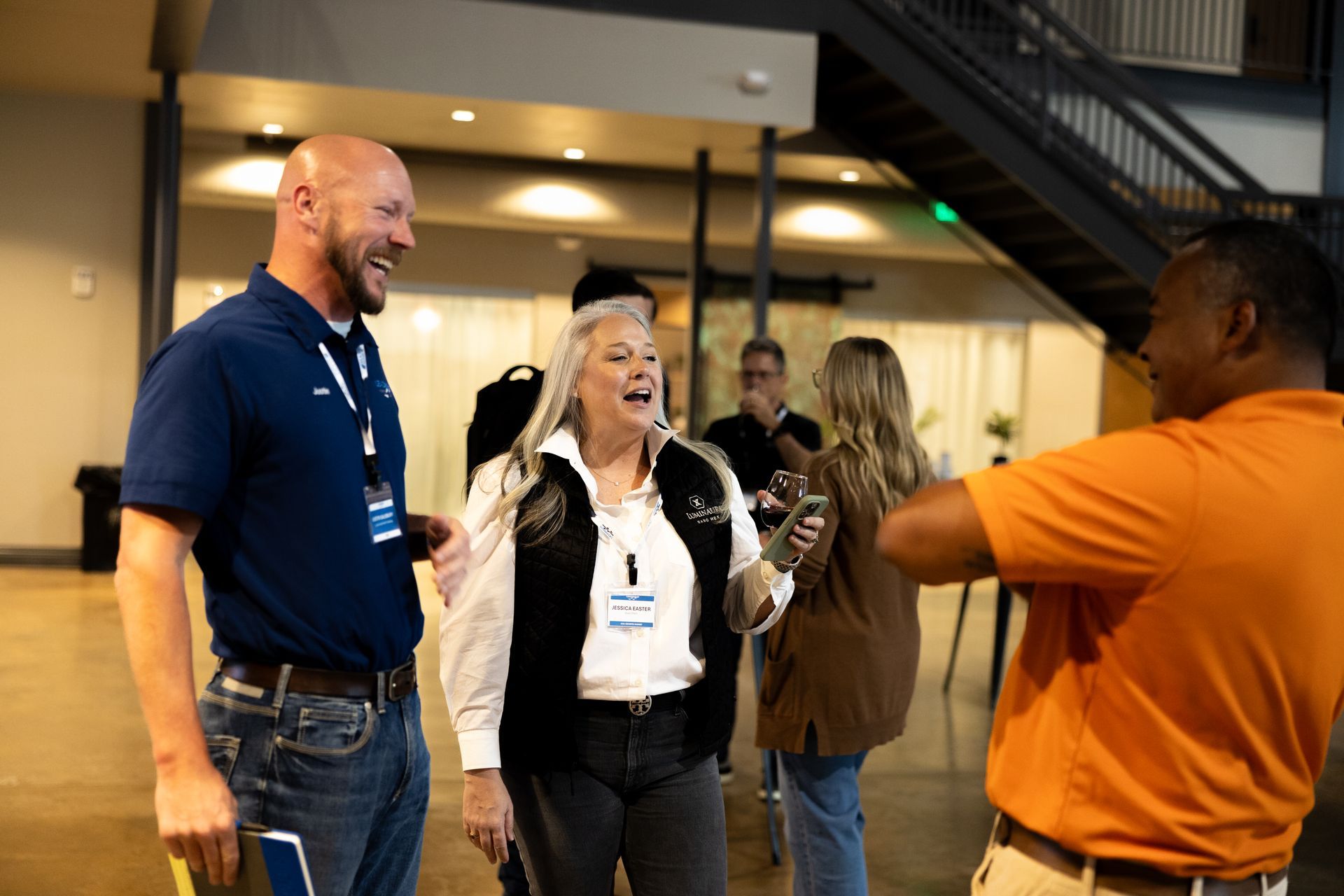People conversing at Leadership Worth Following car wash convention; man in orange shirt, woman with white hair and man with a bald head.
