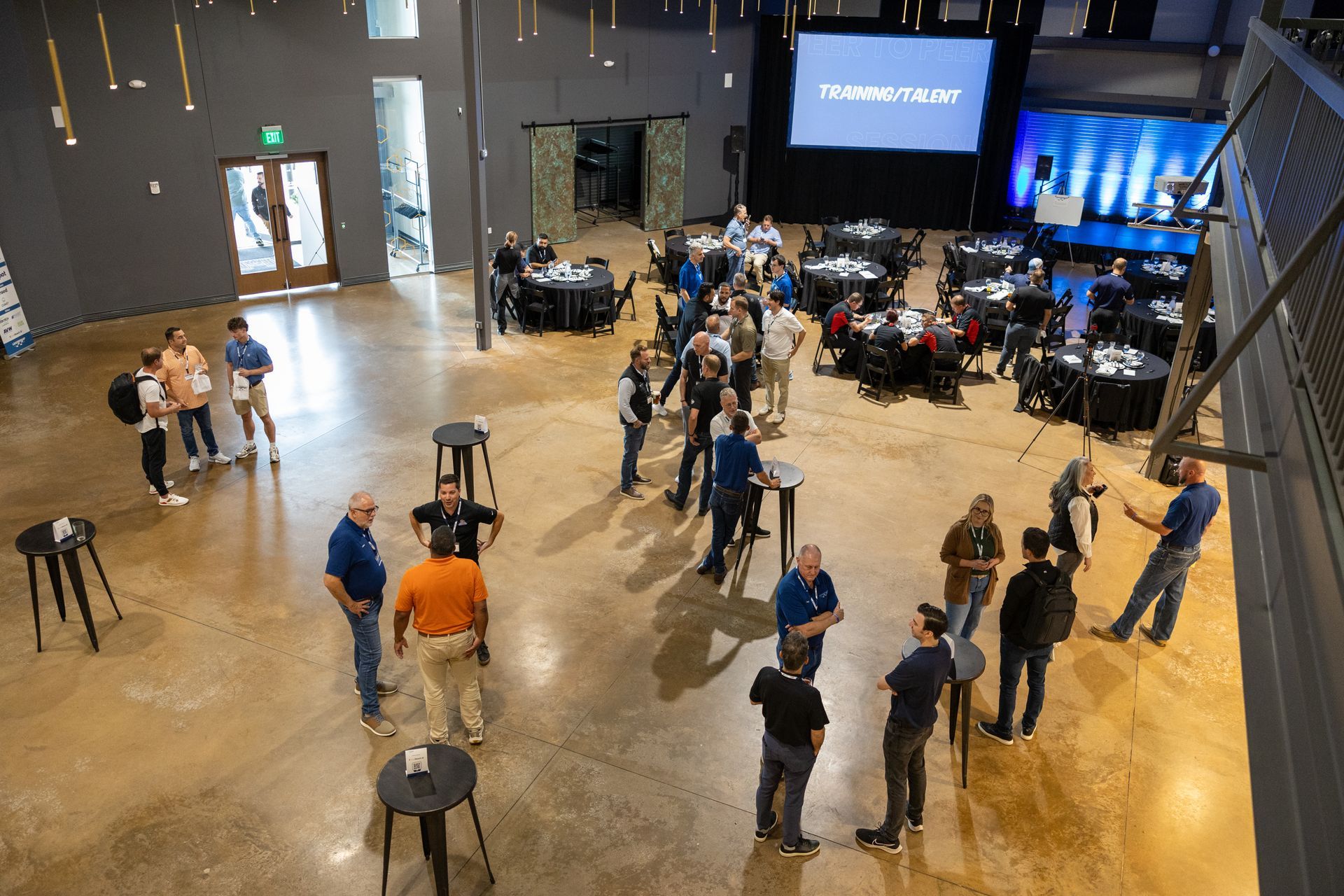 People gather in a large event space at Leadership Worth Following car wash convention and a stage displaying