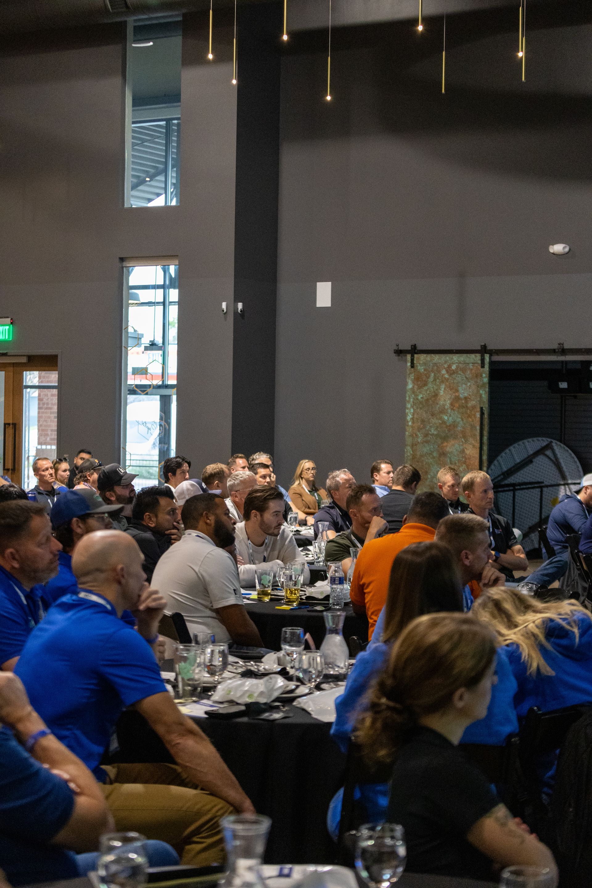 People seated at tables in a large room, listening to a presentation at Leadership Worth Following car wash convention
