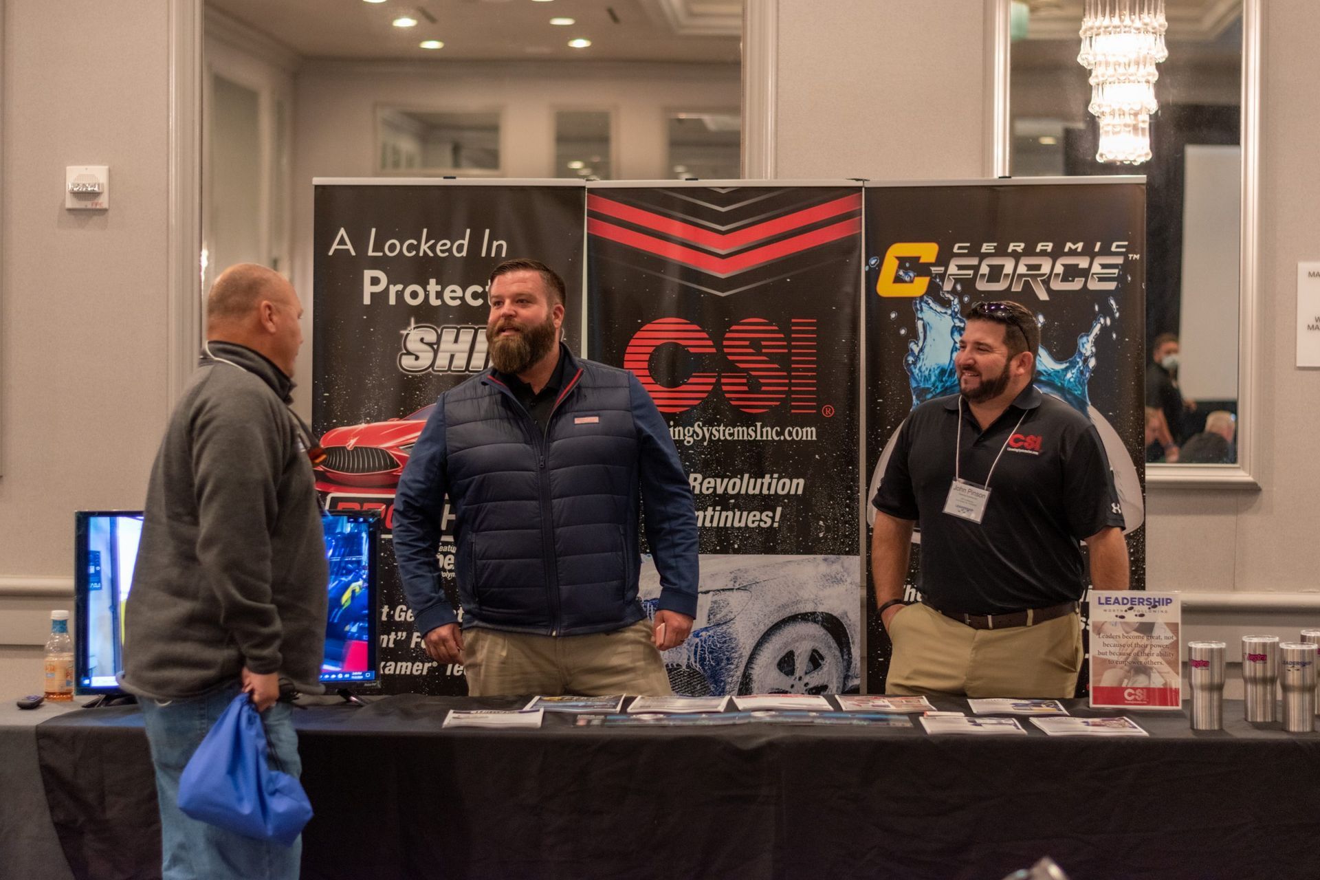 A group of man talking at a booth with car wash signs behind them.