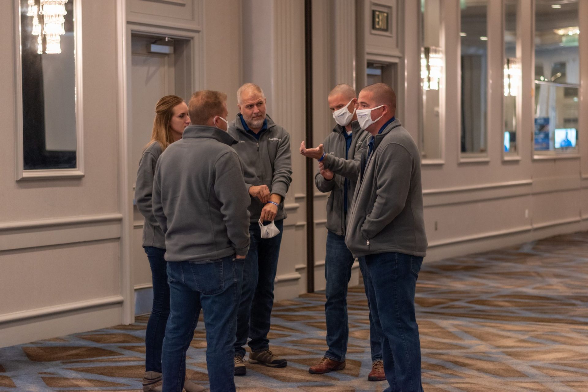 A group of people wearing face masks are standing in a hallway
