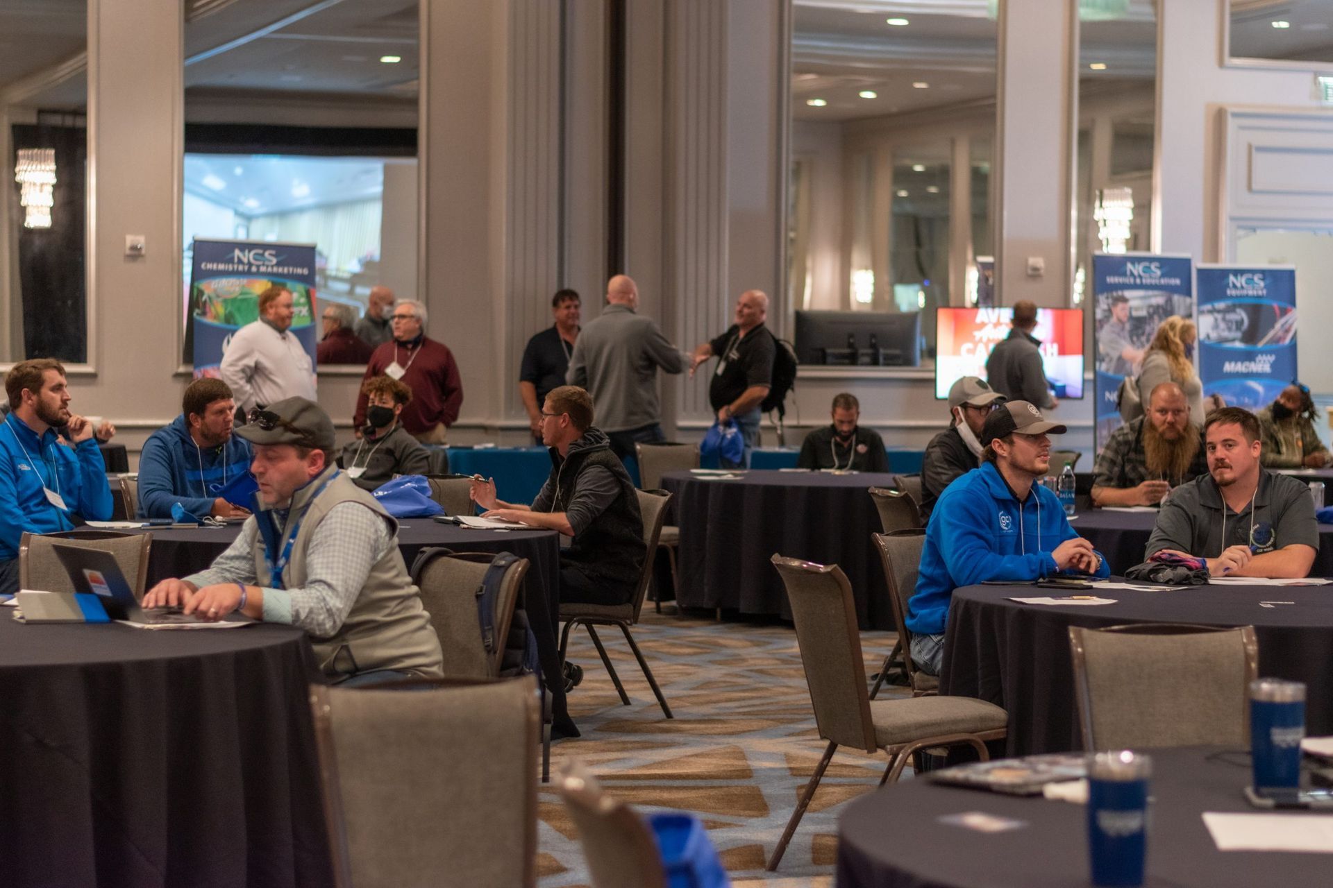 A group of people are sitting at tables in a conference room