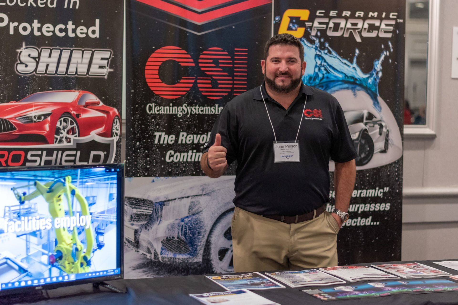 A man giving a thumbs up in front of car wash signs