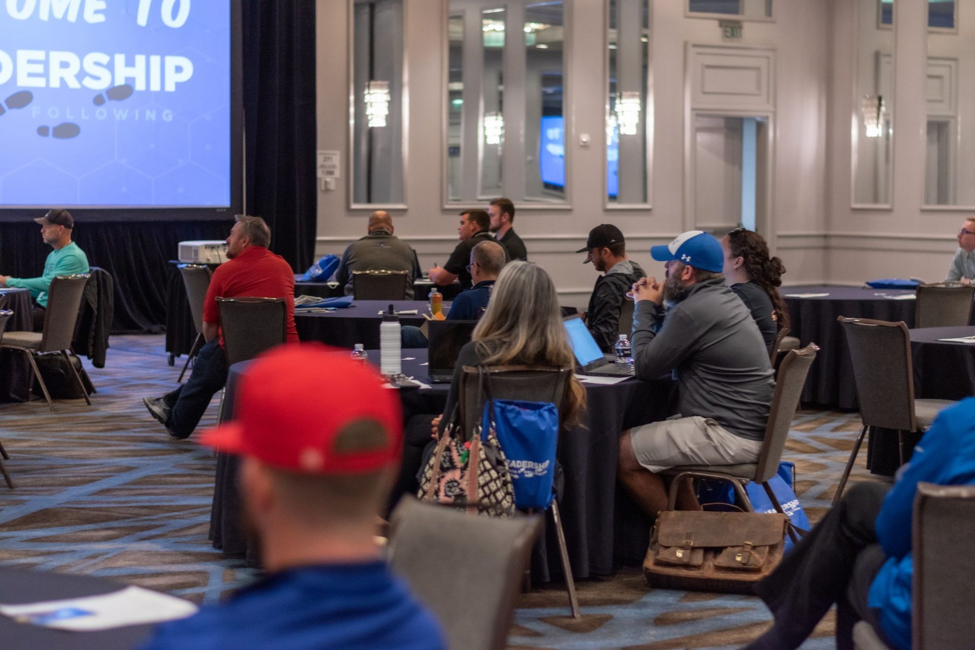 A group of people are sitting at tables in a conference room.