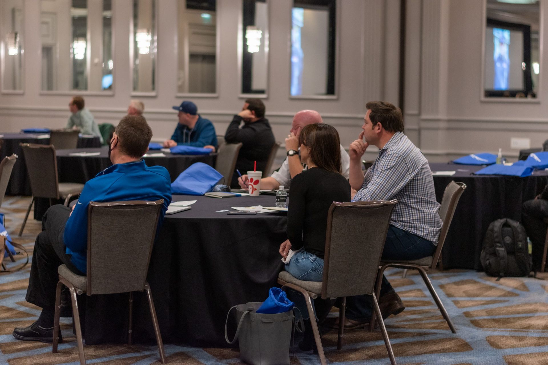 A group of people are sitting at tables in a conference room.
