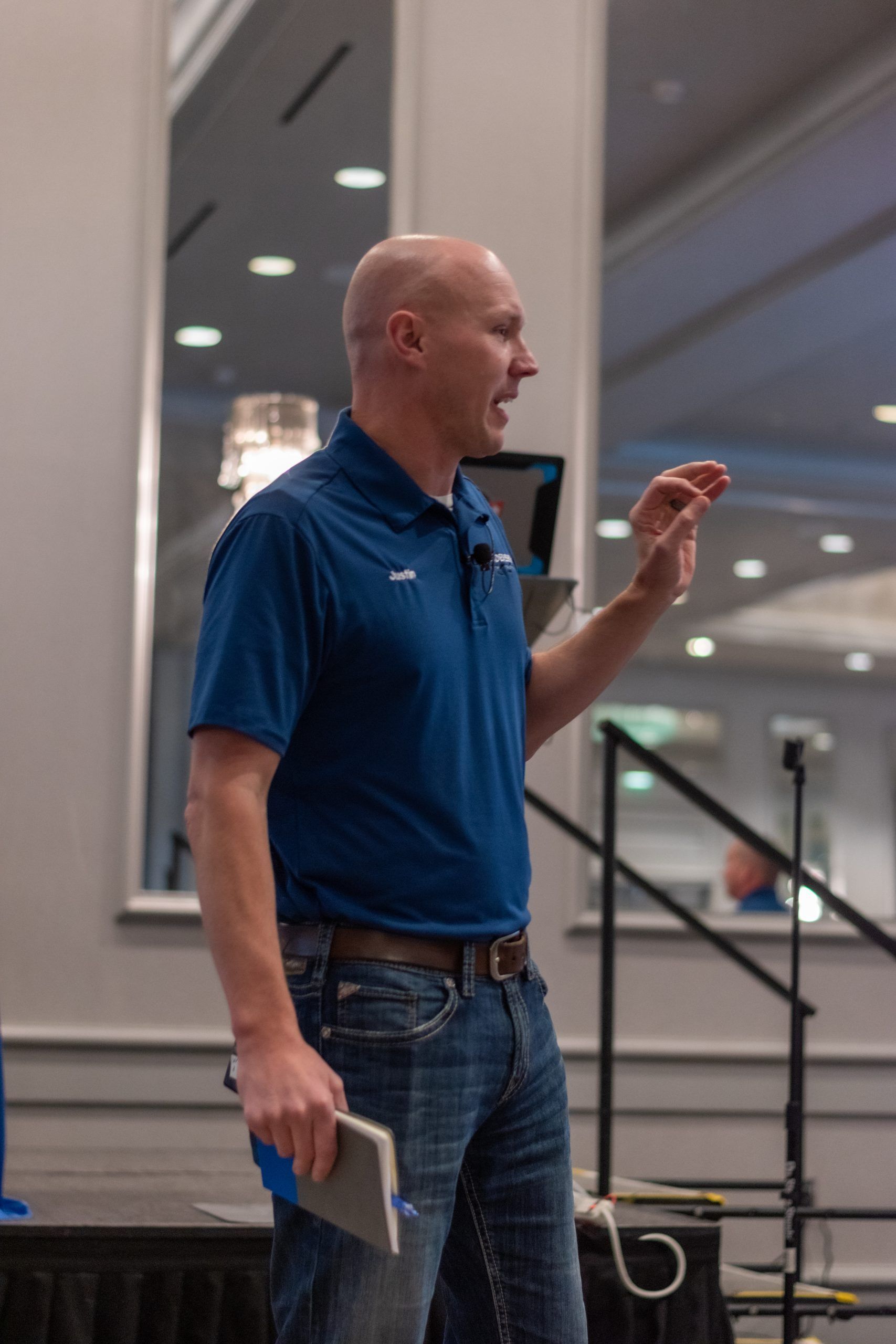 A bald man in a blue shirt is giving a speech