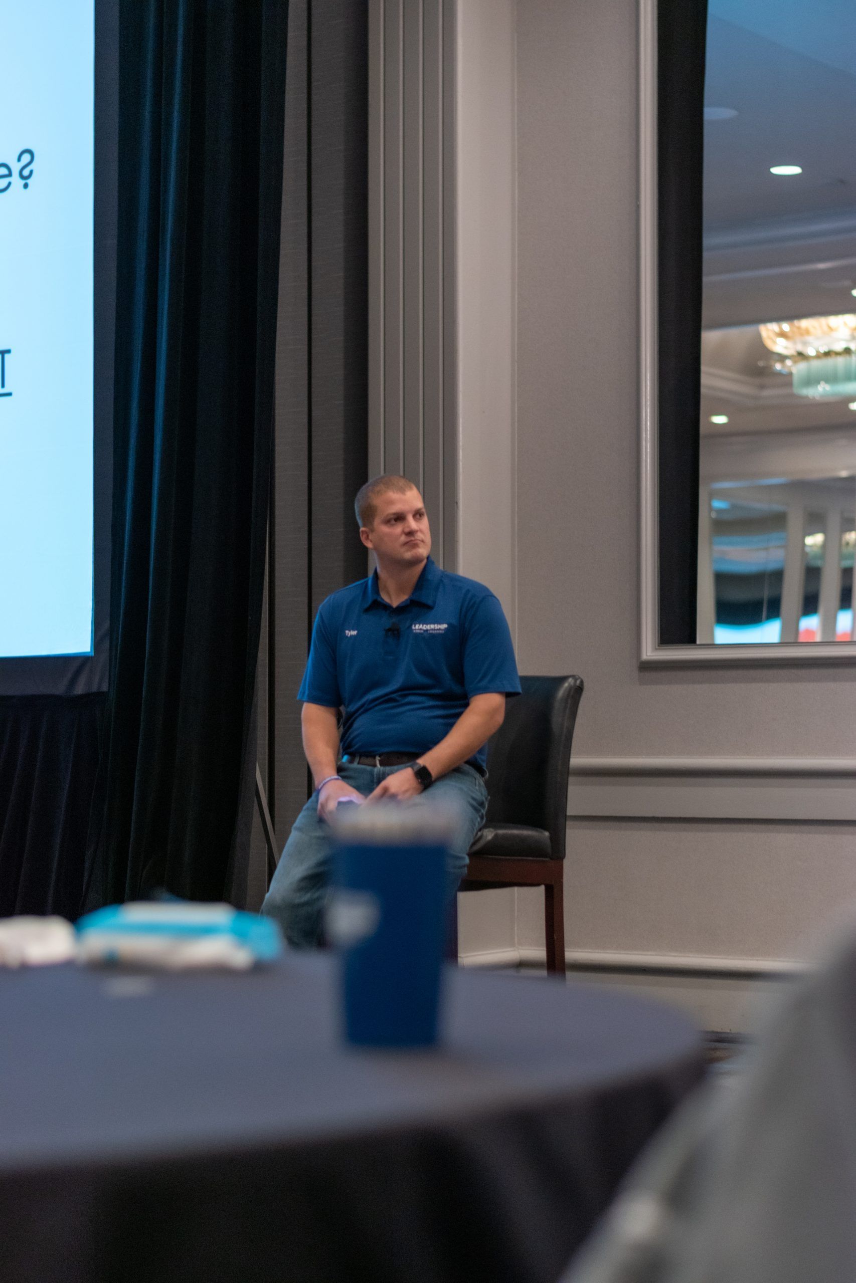 A man is sitting in a chair in front of a screen.