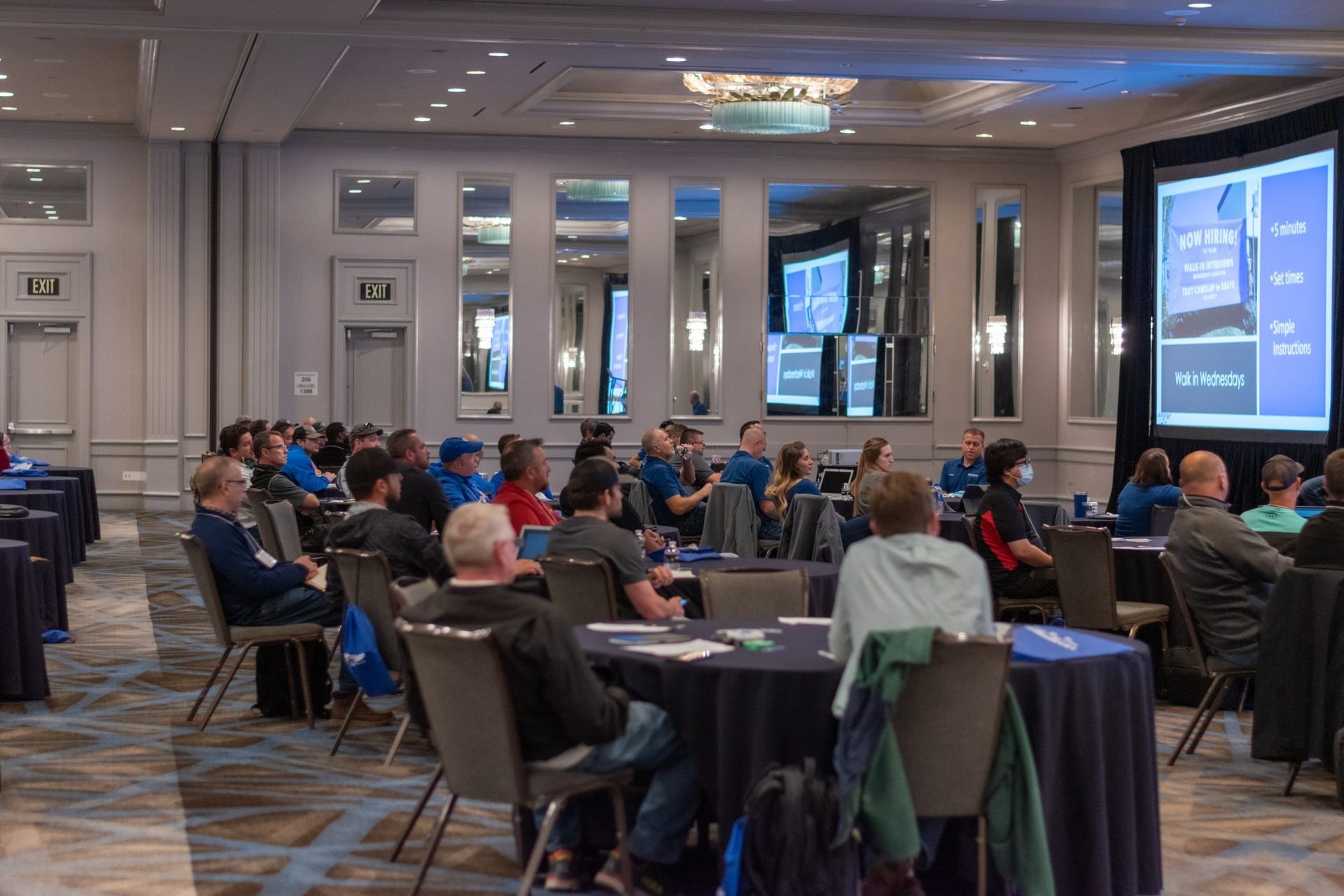 A large group of people are sitting at tables in a conference room.
