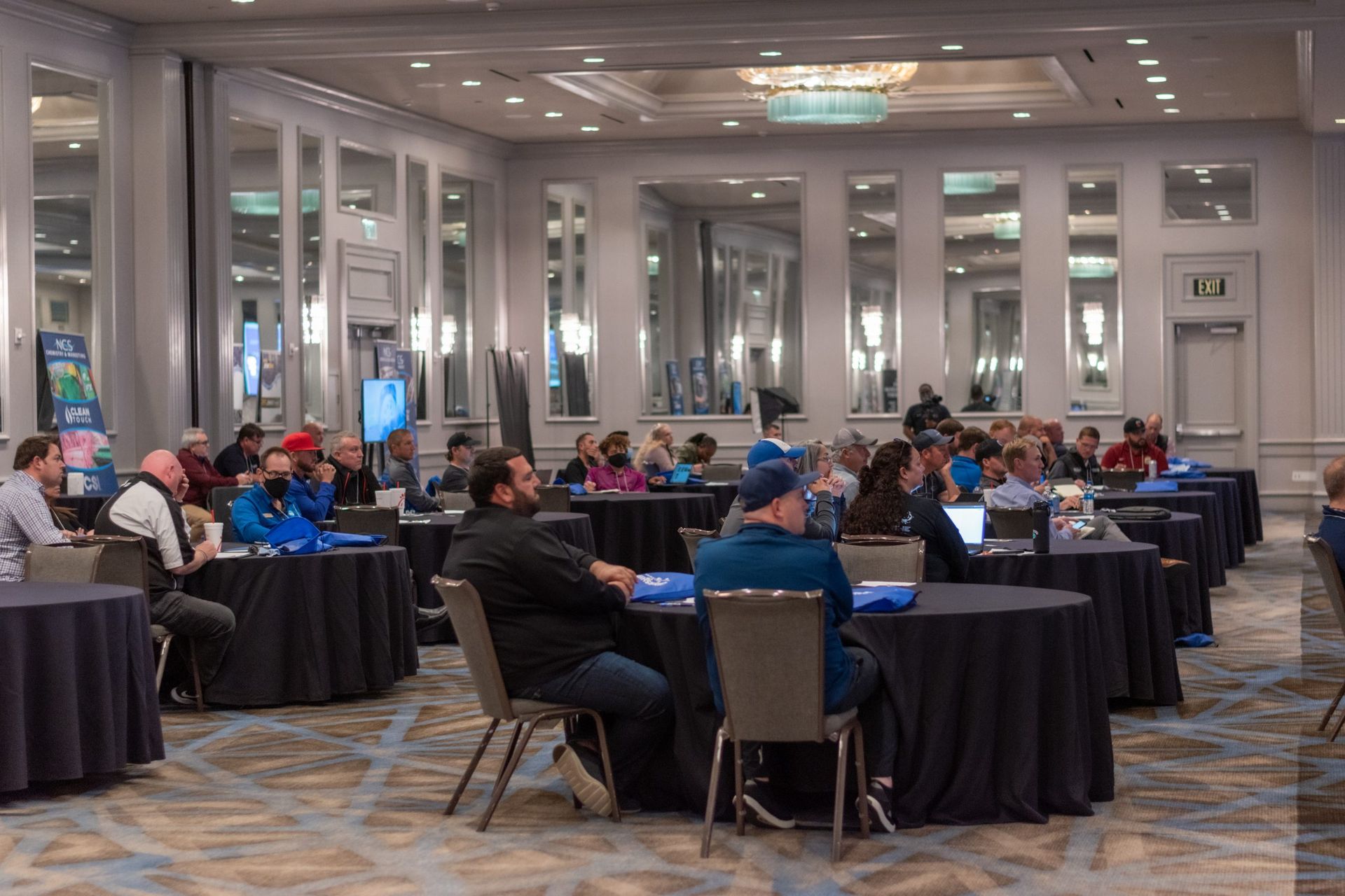 A group of people are sitting at tables in a large room.