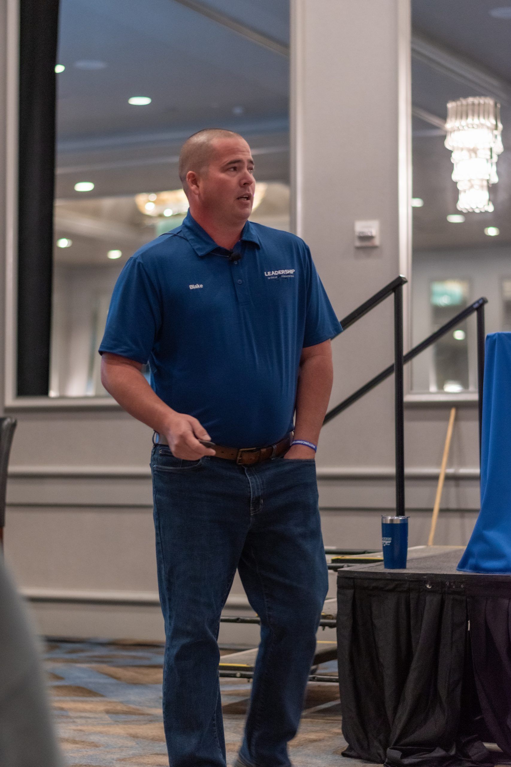 A man in a blue shirt and jeans is standing in a room.