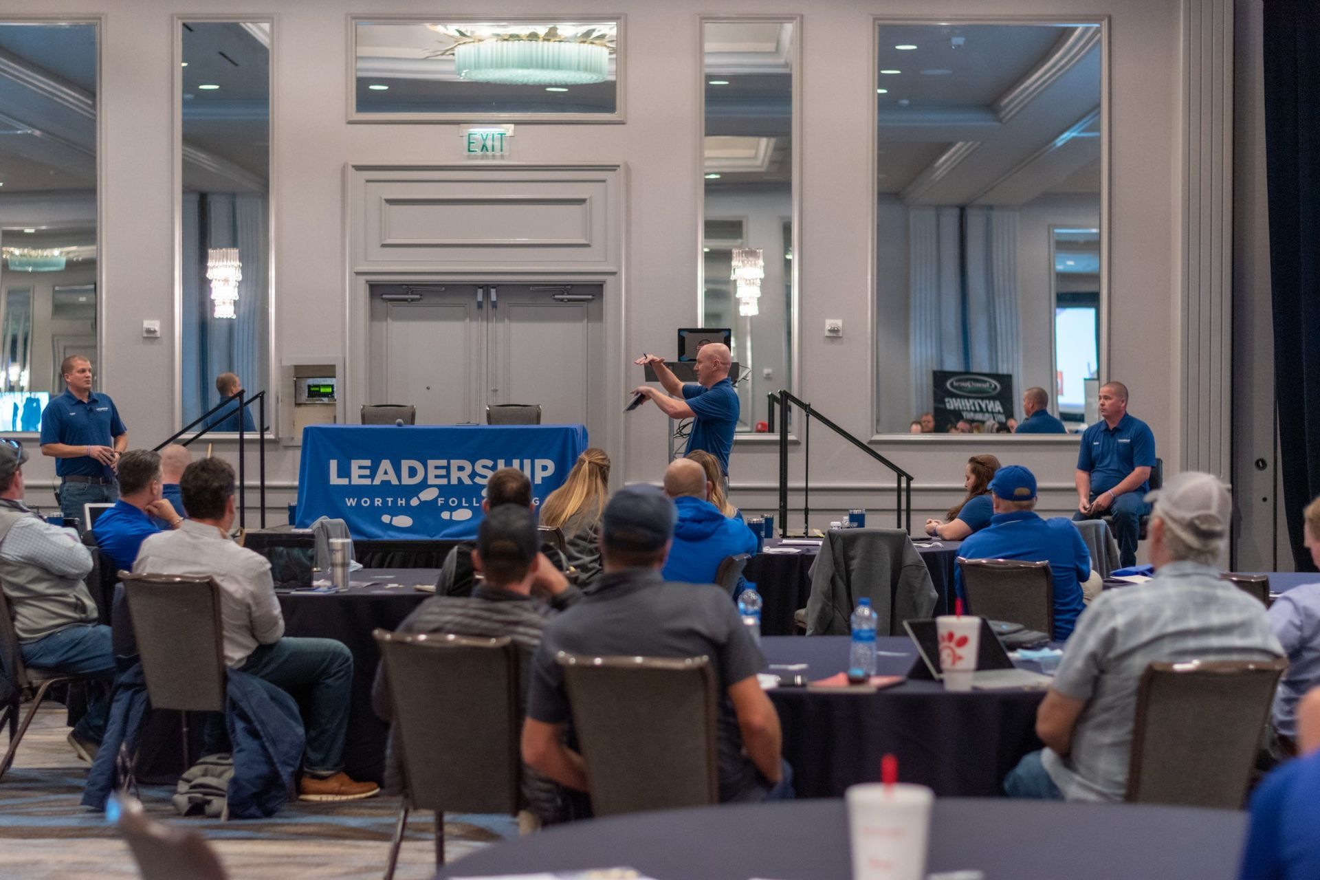 A group of people are sitting at tables in a conference room.