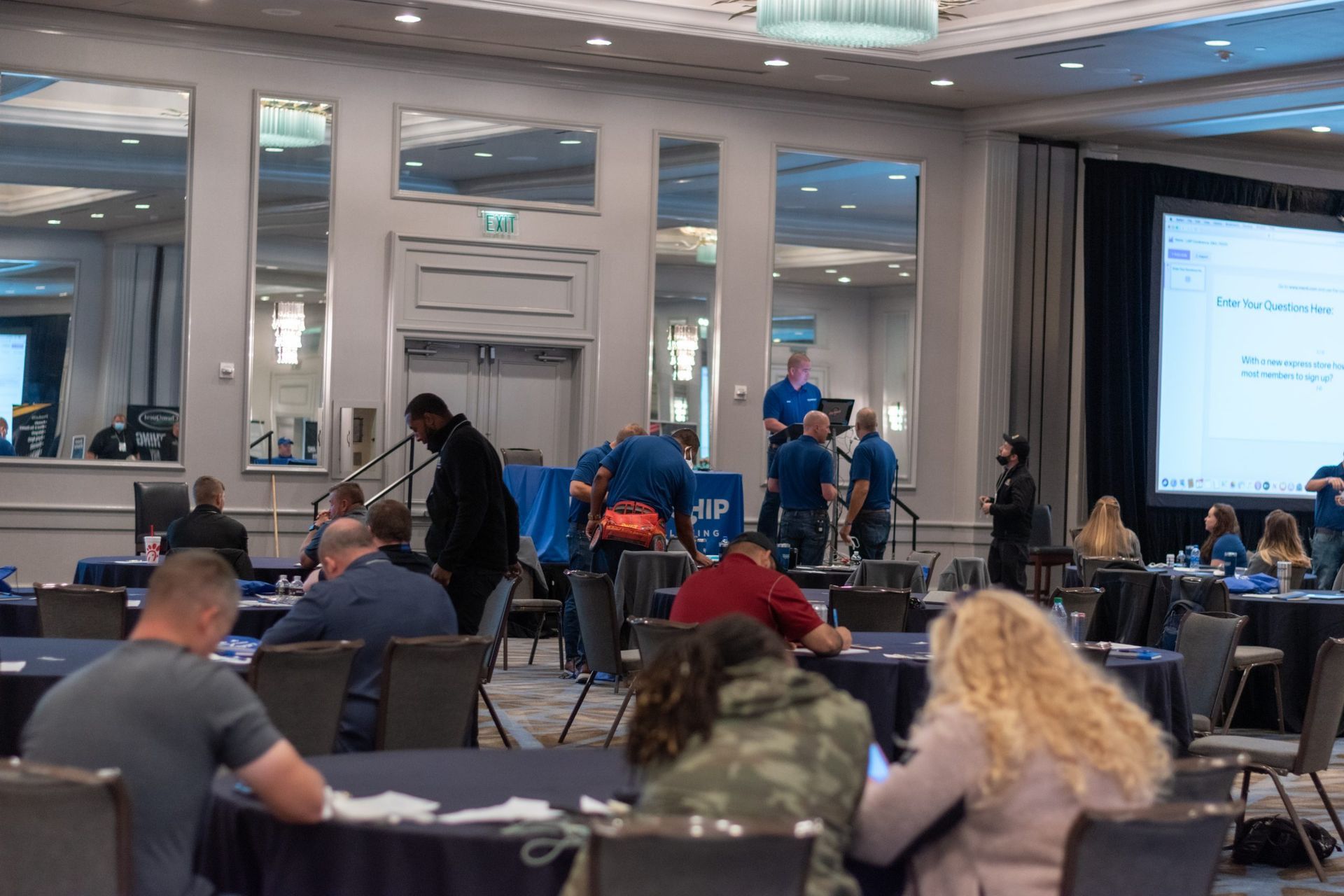 A group of people are sitting at tables in a conference room.