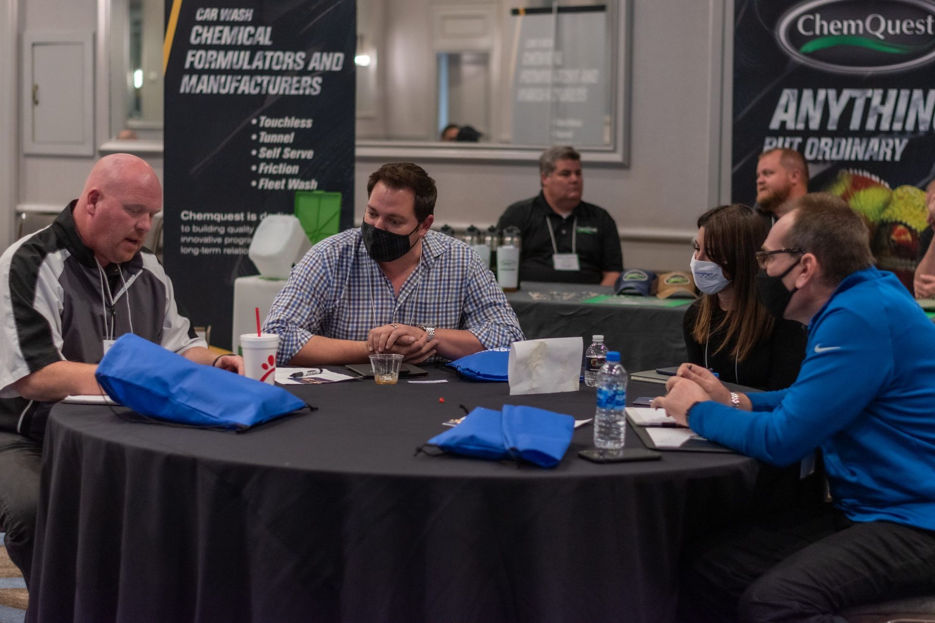A group of people are sitting around a table wearing masks.