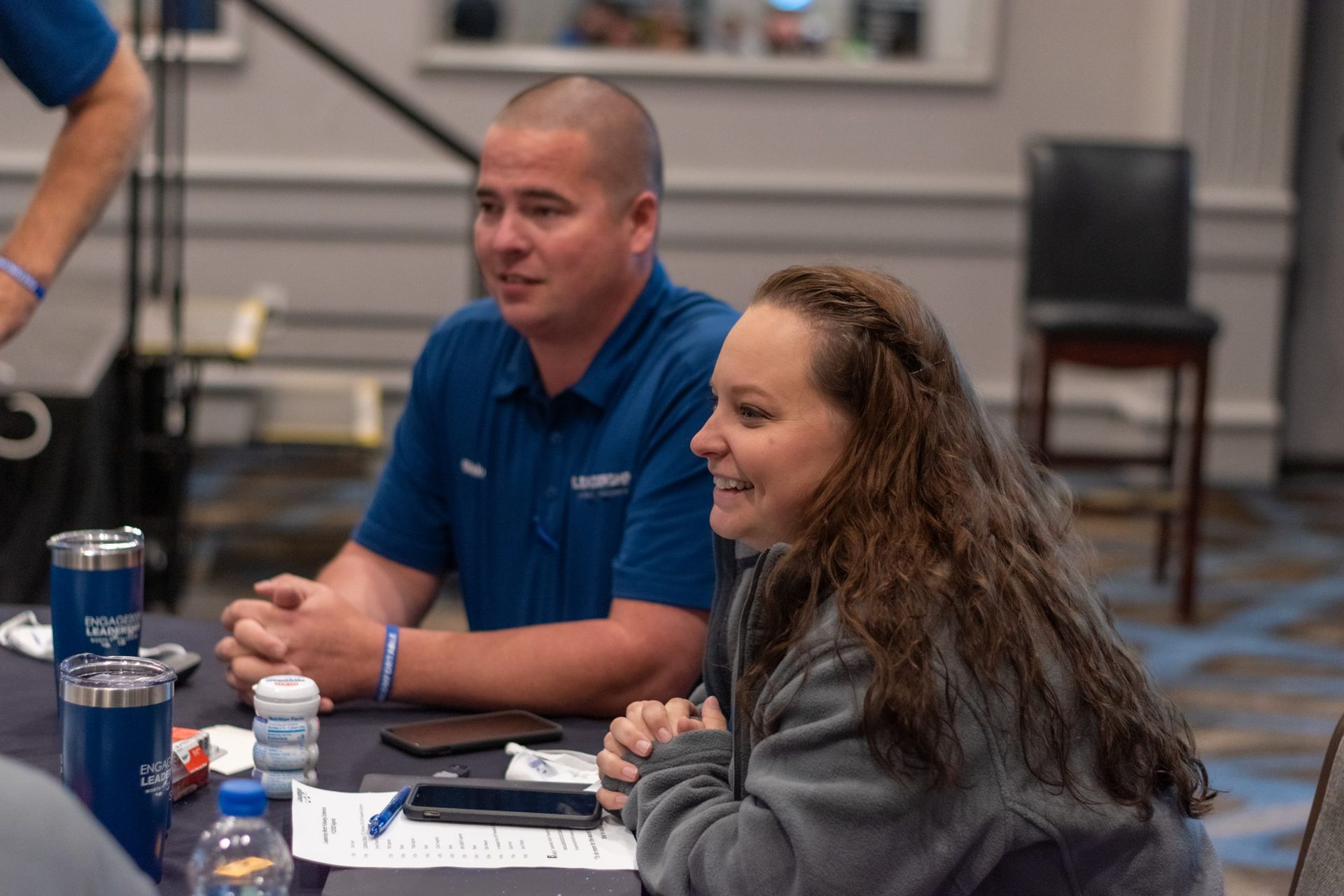 A man and a woman are sitting at a table talking to each other.