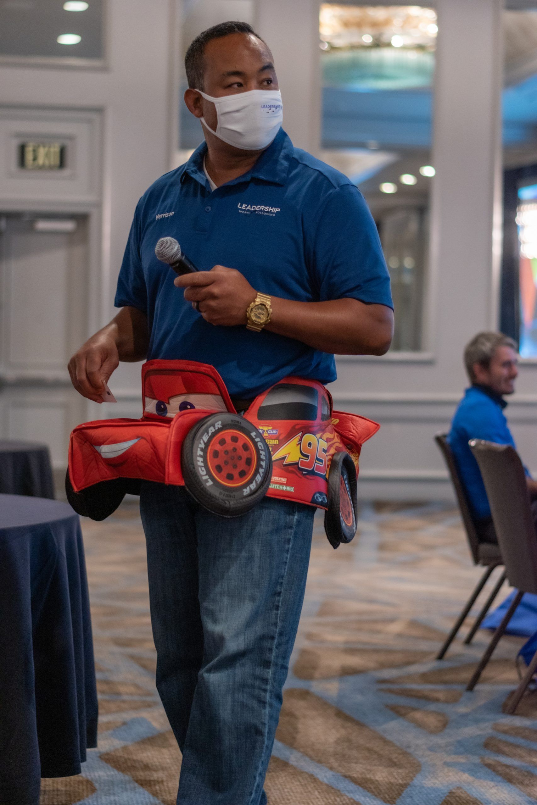 A man wearing a mask is holding a toy car on his waist.