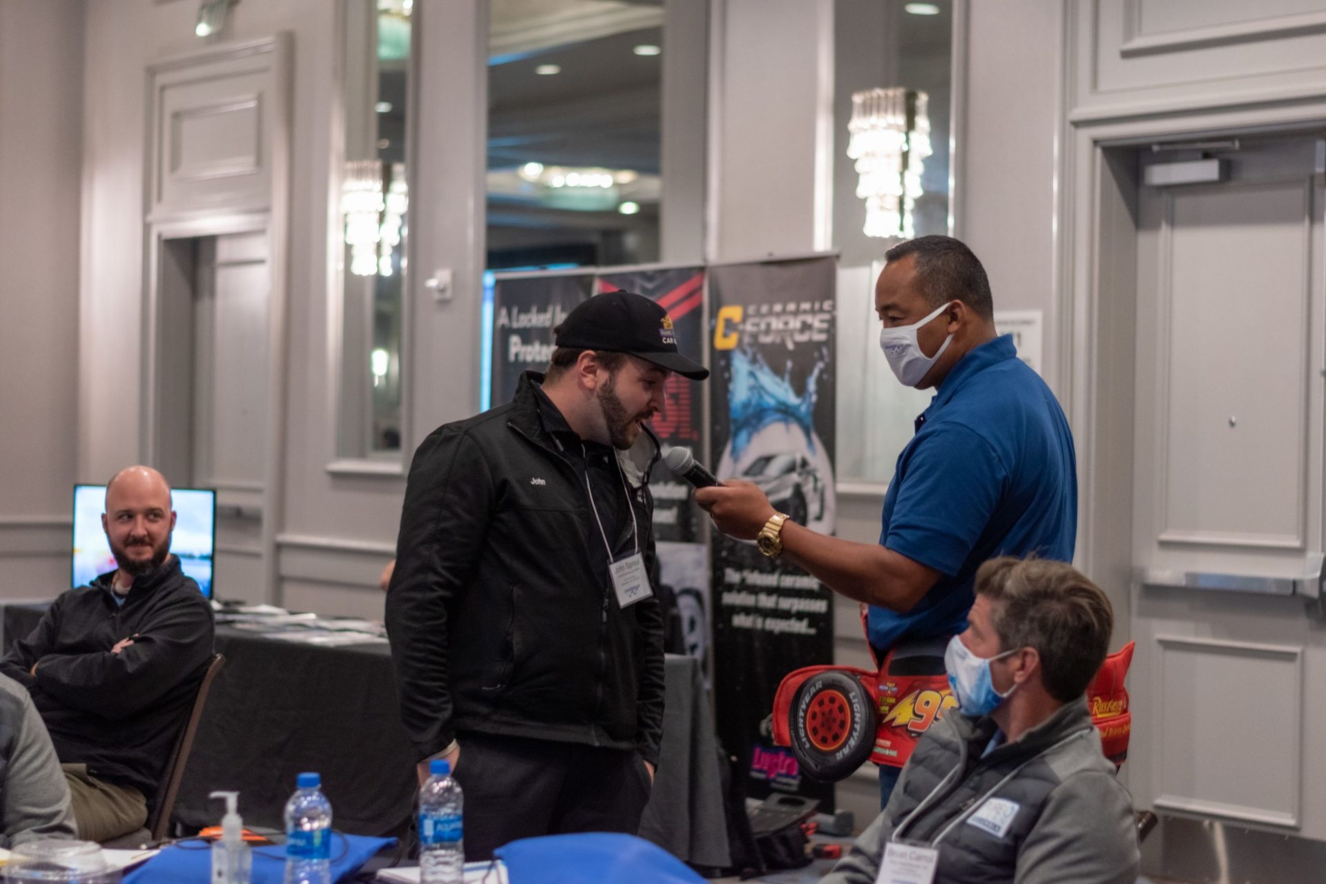 A group of men wearing face masks are talking to each other in a room.