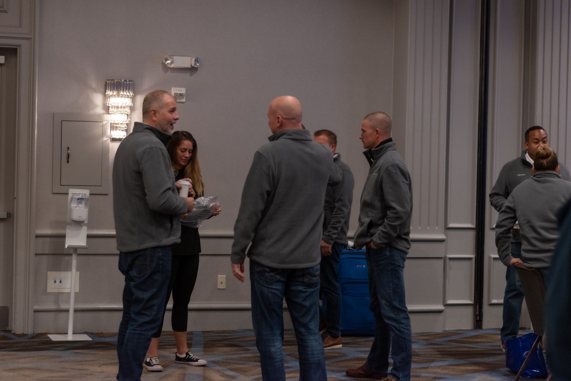 A group of people are standing in a room talking to each other.