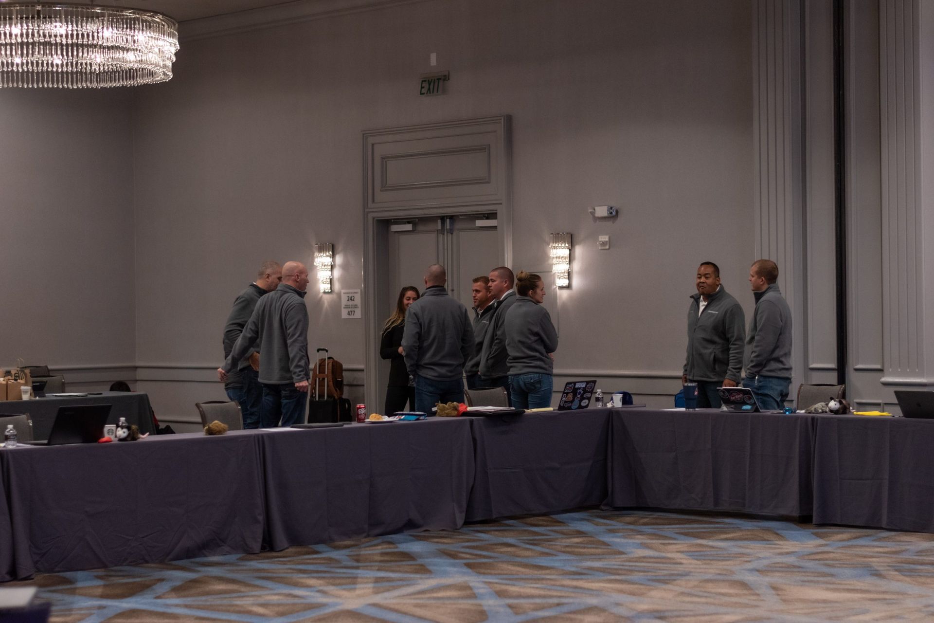 A group of people are standing around a long table in a conference room.