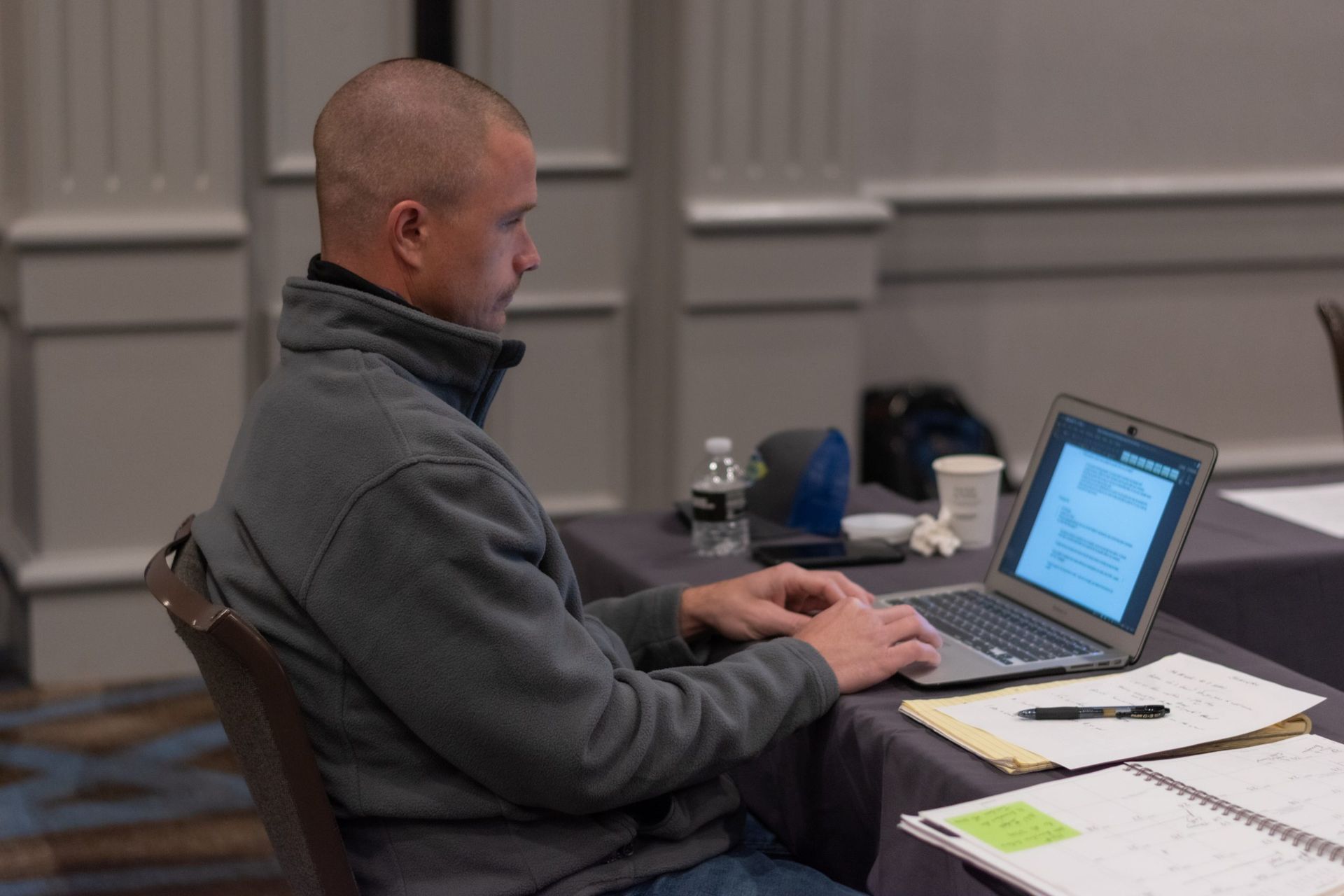 A man is sitting at a table using a laptop computer.