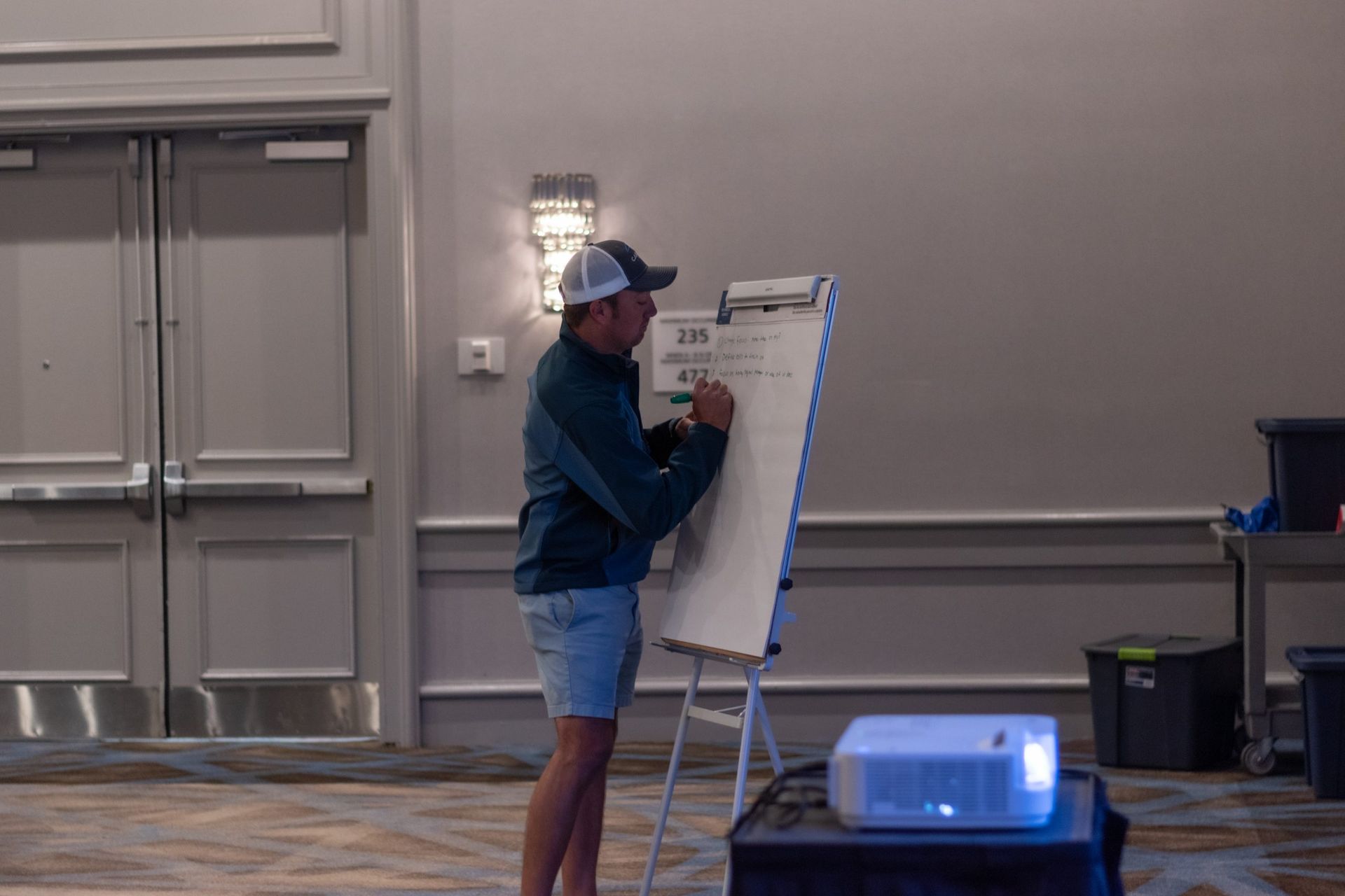 A man is writing on a whiteboard in a room.