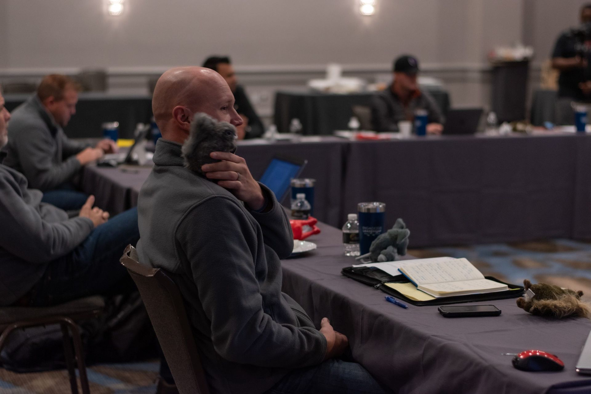 A man is sitting at a table talking on a cell phone.