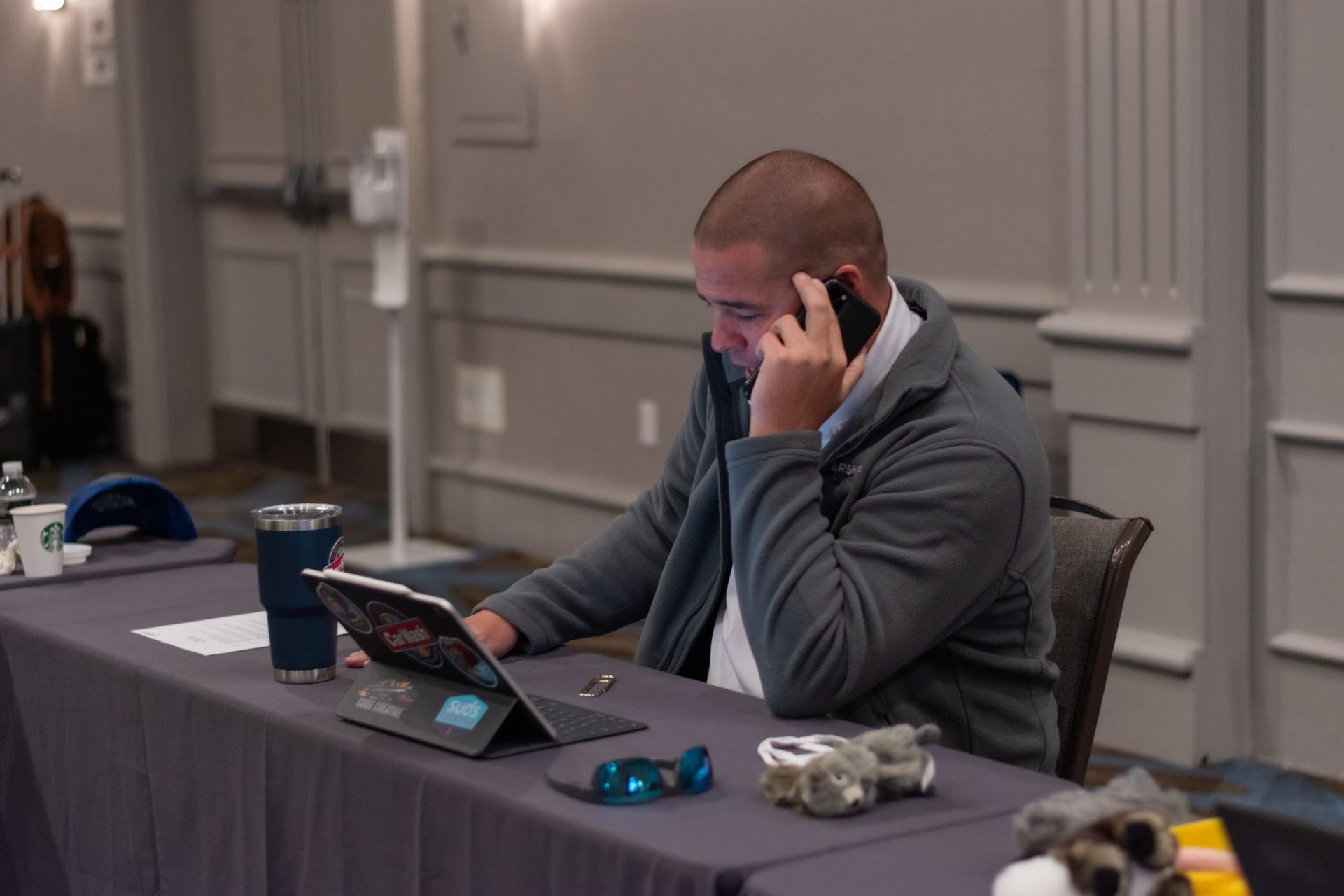A man is sitting at a table talking on a cell phone.