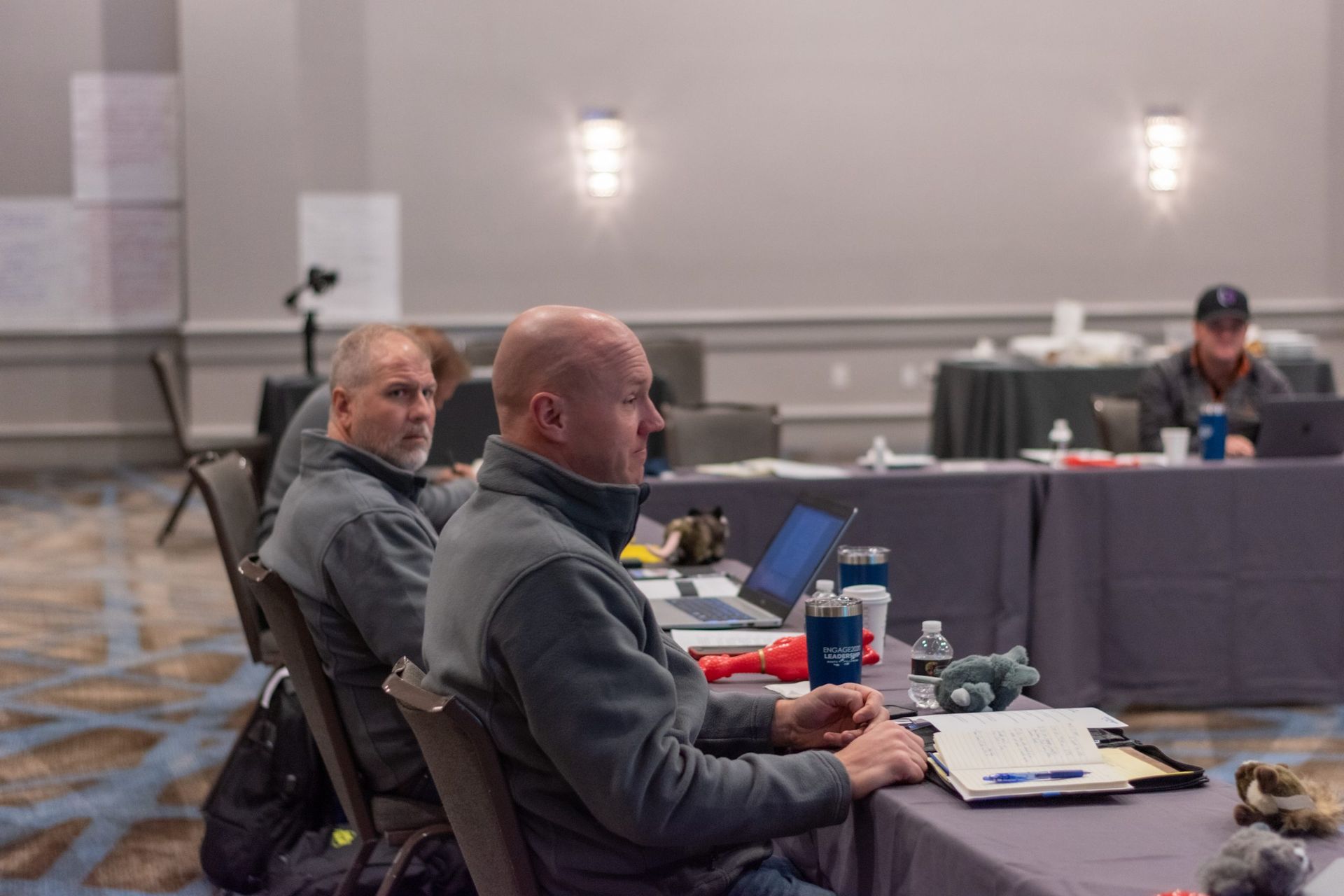 A group of men are sitting at tables in a conference room.