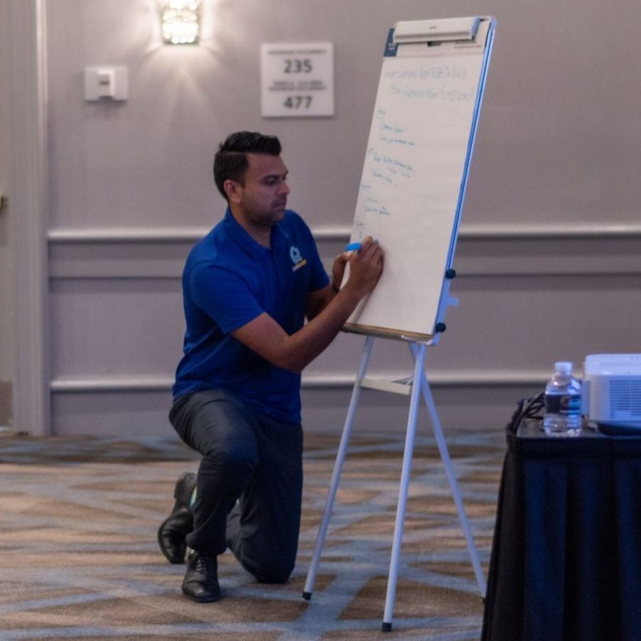 A man in a blue shirt is writing on a white board