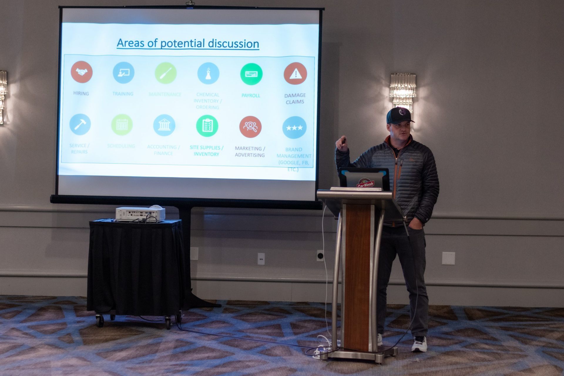 A man is giving a presentation in front of a projector screen.