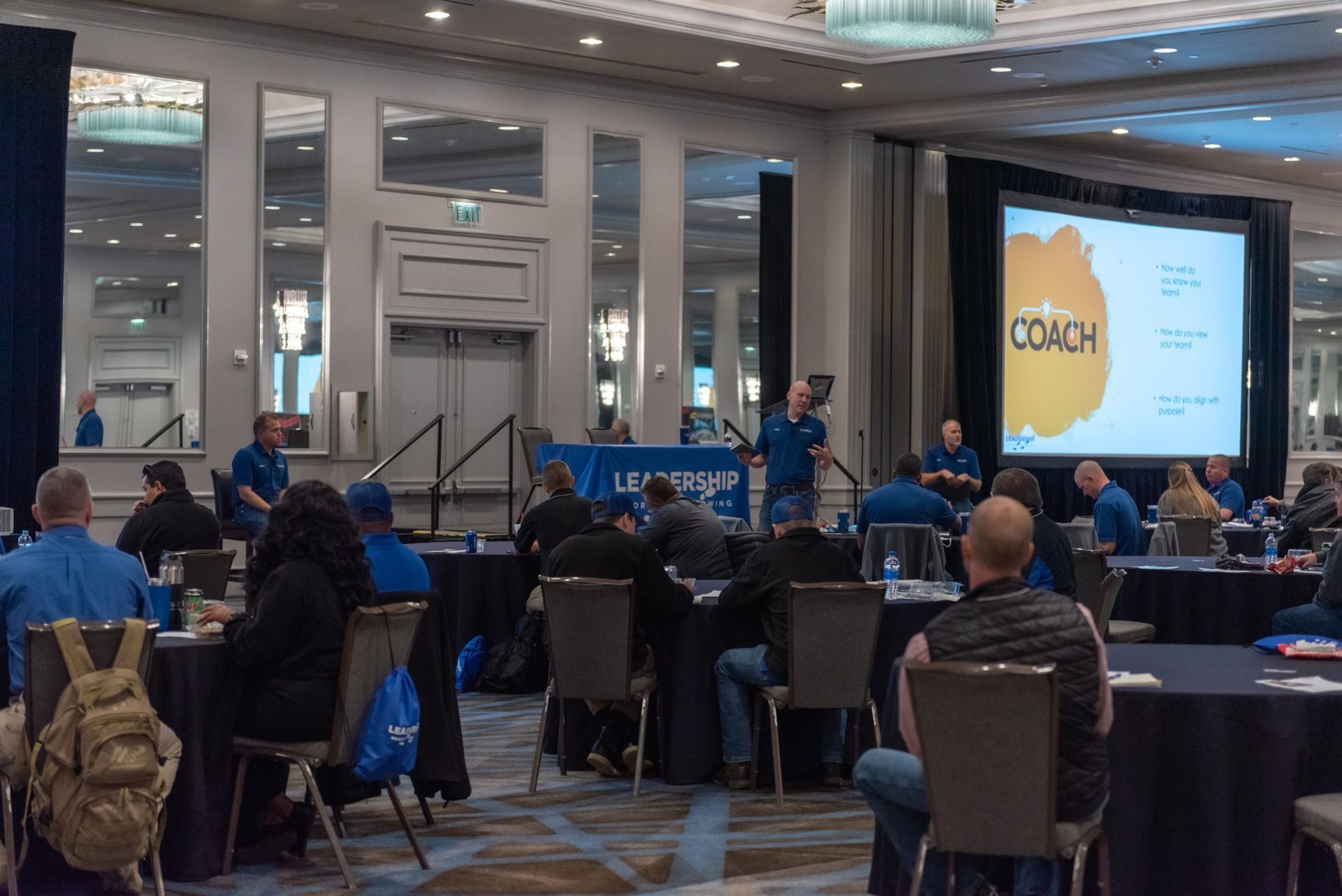A group of people are sitting at tables in a conference room.