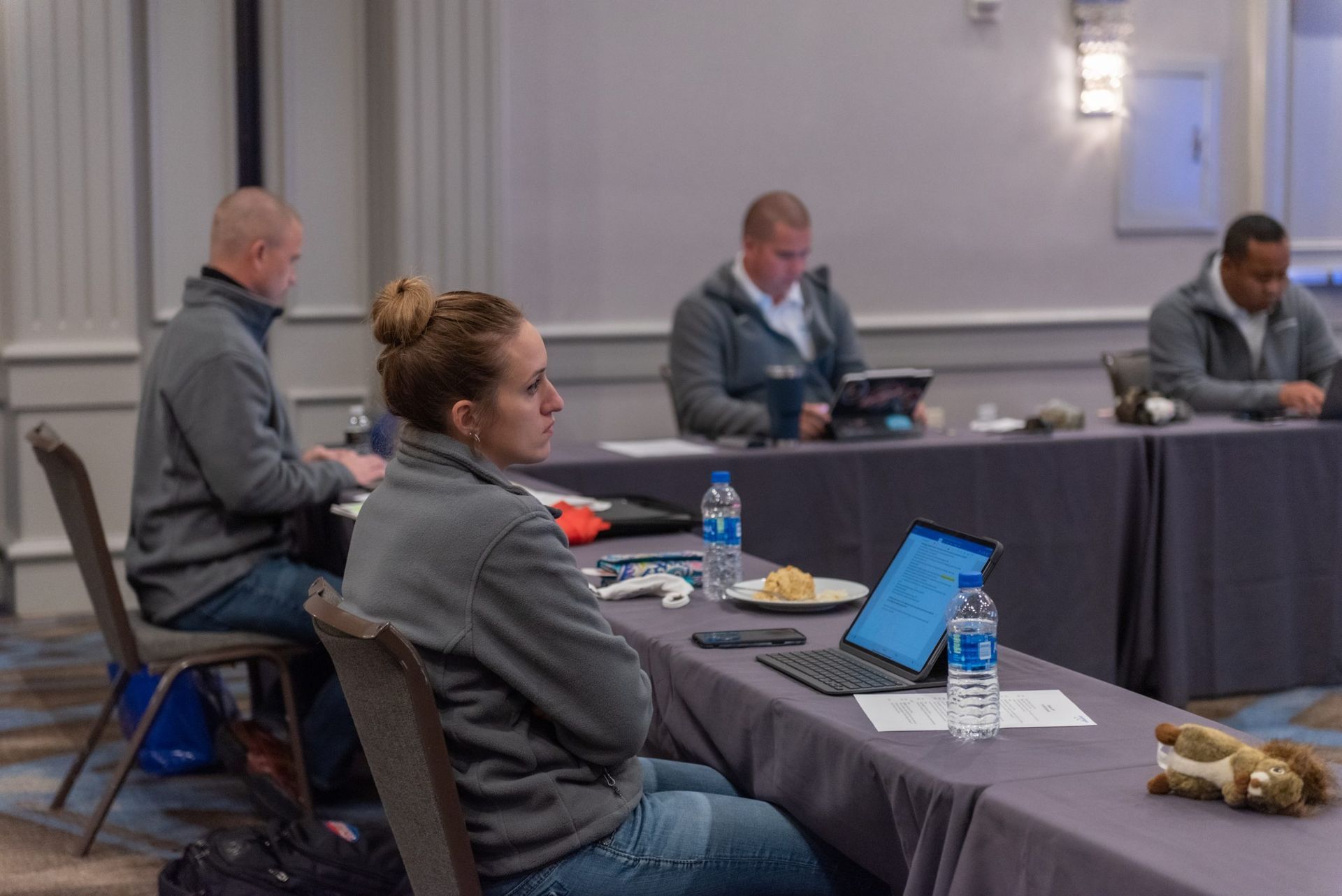 A group of people are sitting at a table with laptops.