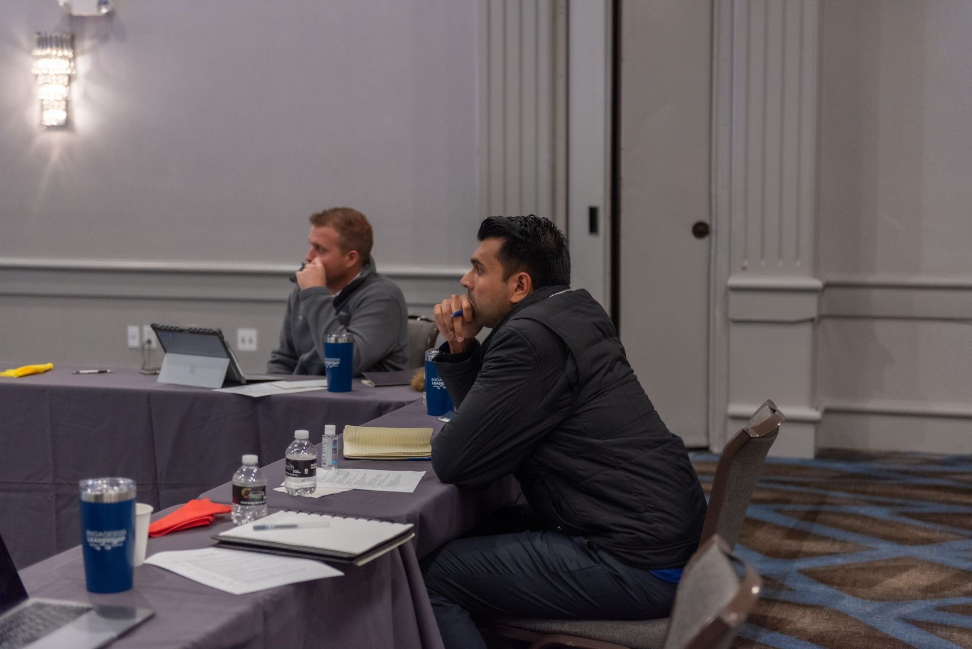 A group of men are sitting at tables in a conference room.