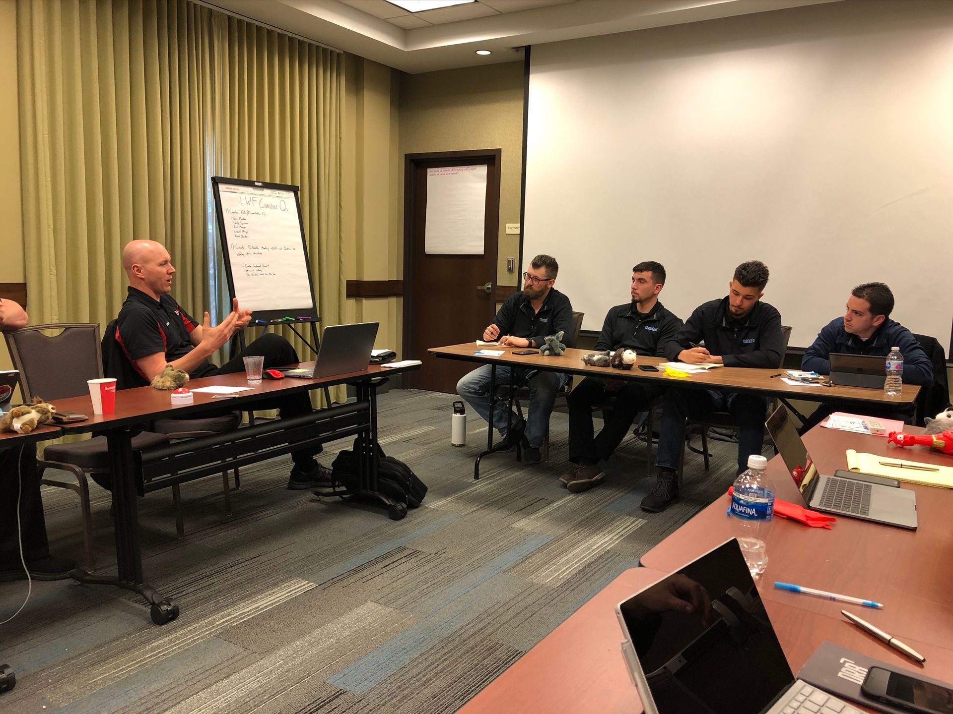 A group of men are sitting at tables in a conference room.