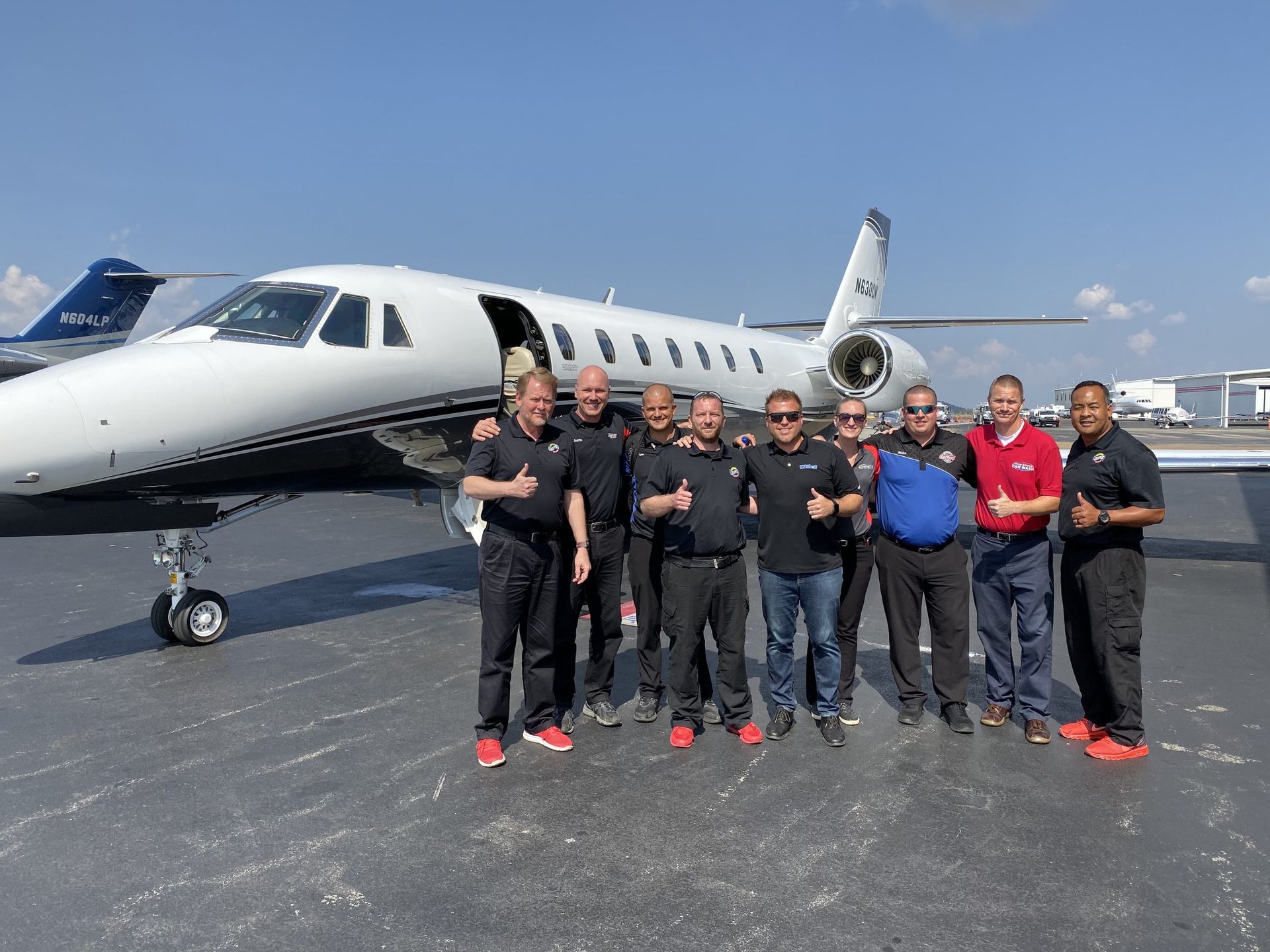 A group of men are posing for a picture in front of an airplane
