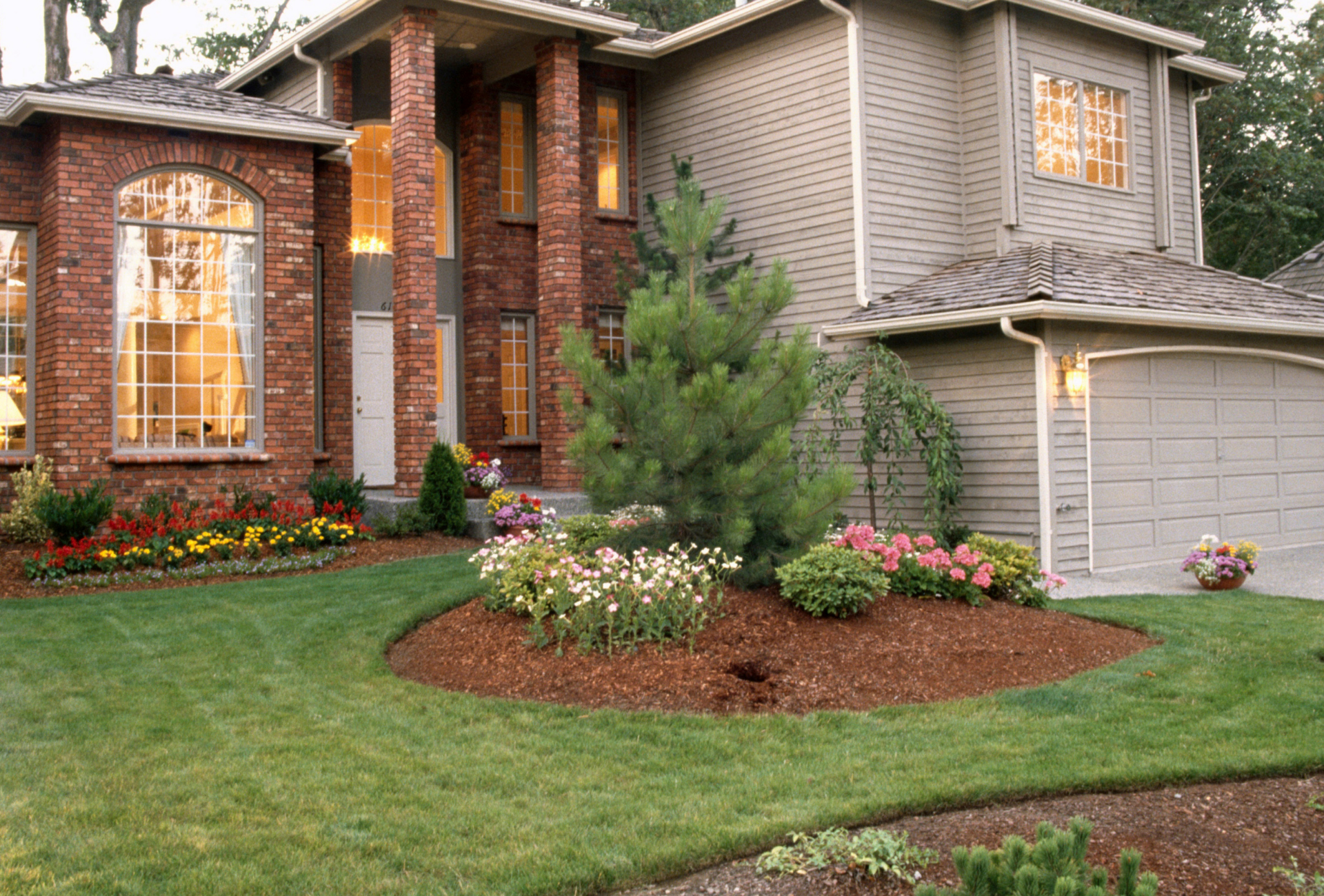 A house with a lush green lawn and flowers in front of it