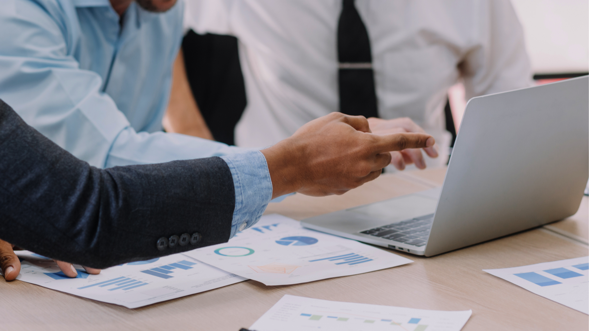 Man with glasses, working on a laptop at a desk with a coffee mug and papers.