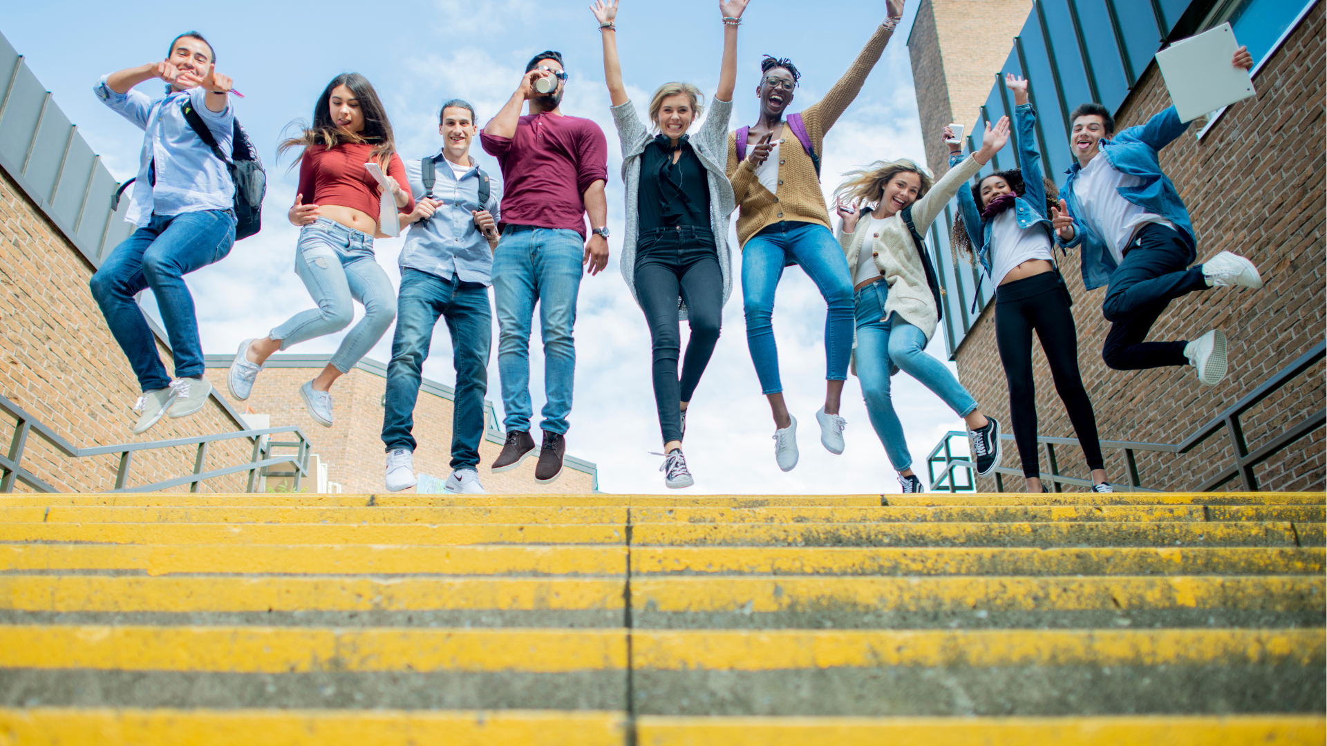 Man with glasses, working on a laptop at a desk with a coffee mug and papers.