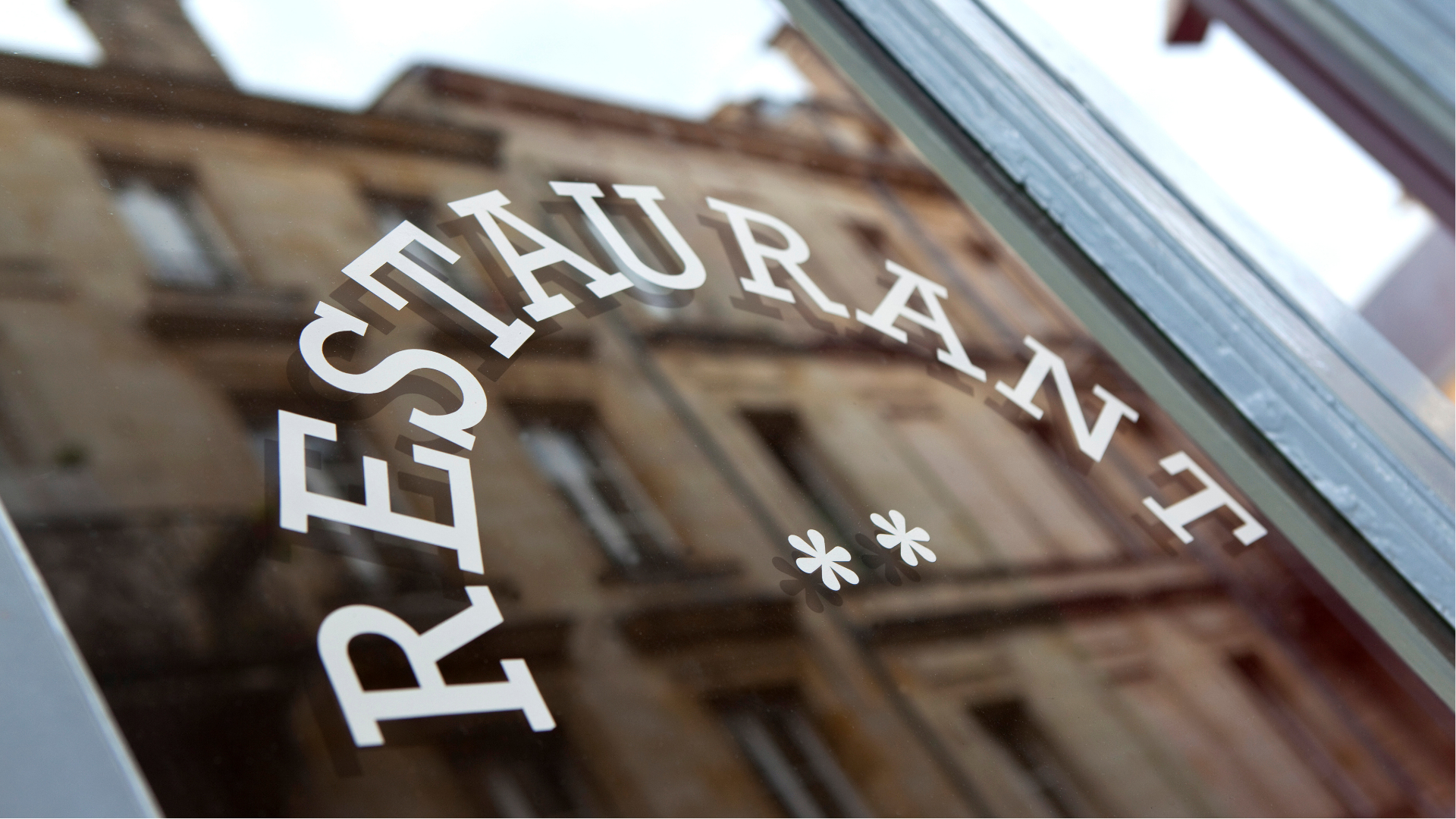 Man with glasses, working on a laptop at a desk with a coffee mug and papers.