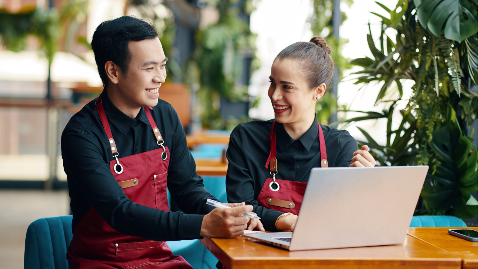 People at a table looking at laptops. They are smiling and working in a modern office.