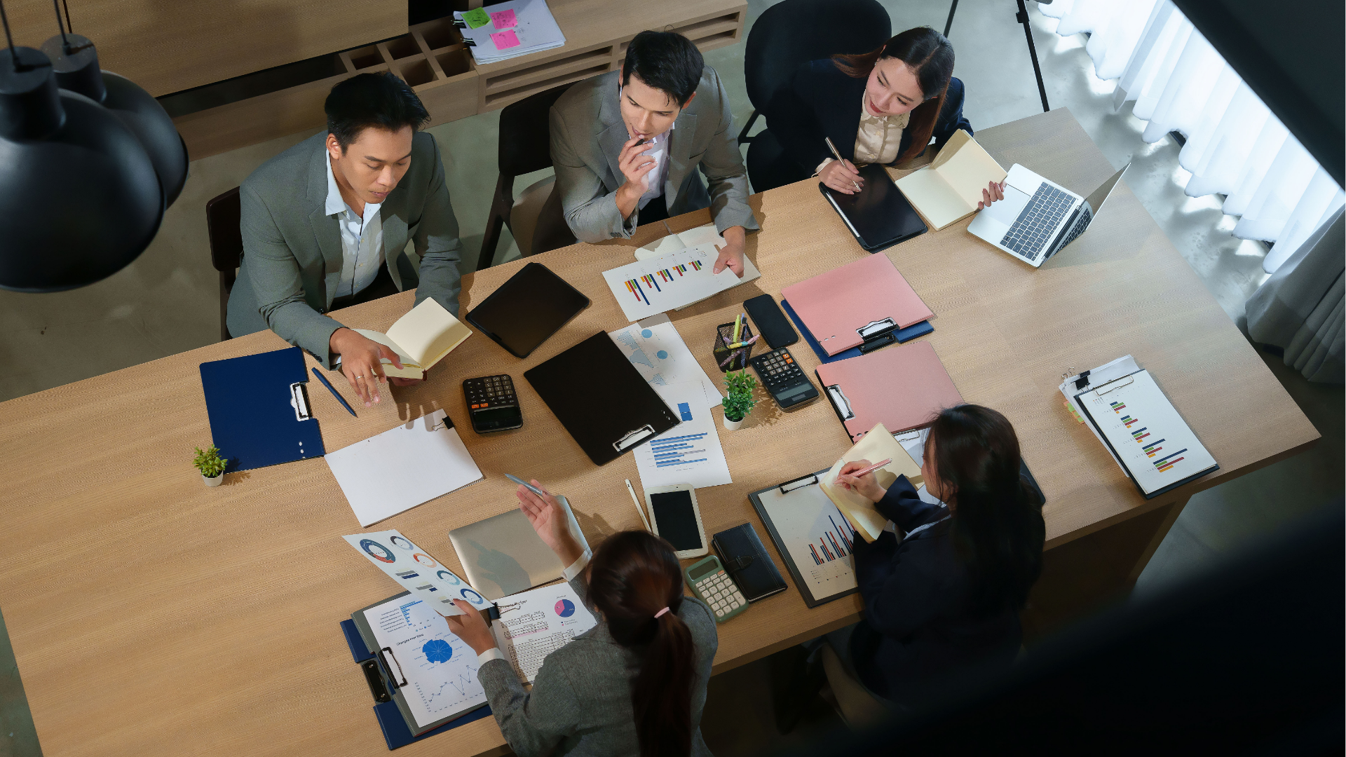 Man typing on keyboard, coding on dual computer monitors, at a desk in a dimly lit room.