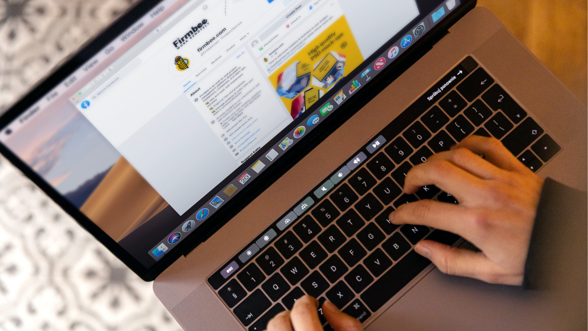 Man with glasses, working on a laptop at a desk with a coffee mug and papers.