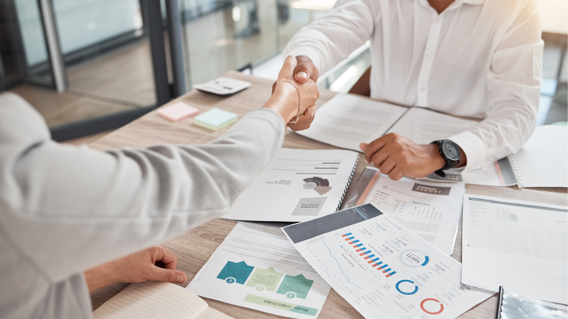 Man typing on keyboard, coding on dual computer monitors, at a desk in a dimly lit room.