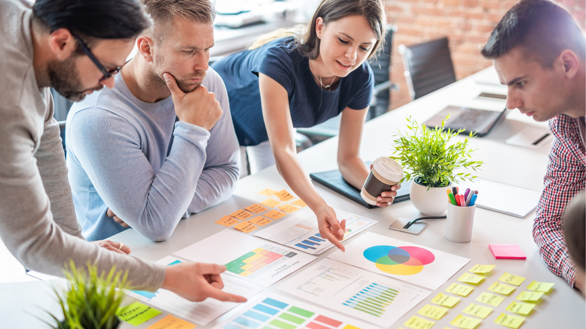 People at a table looking at laptops. They are smiling and working in a modern office.