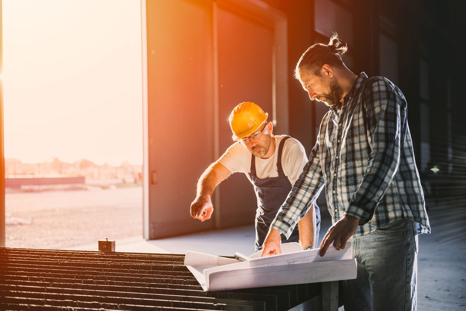 two construction workers are looking at a blueprint on a construction site .