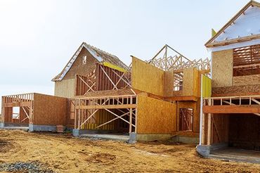 a row of wooden houses are being built in a construction site .